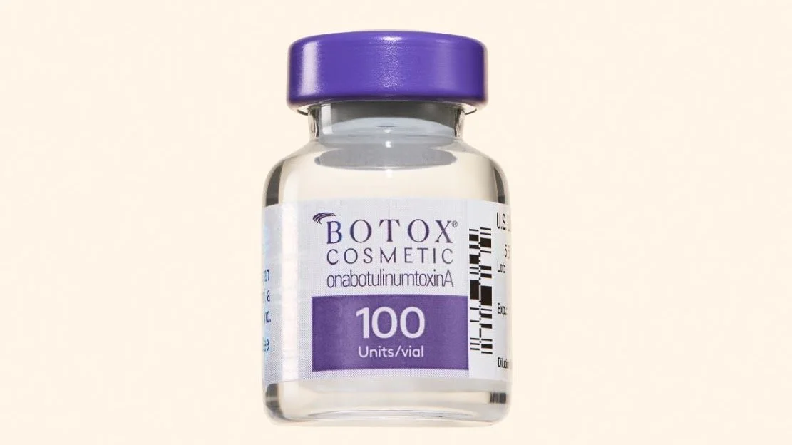 A small glass vial labeled Botox Cosmetic with a purple cap, containing 100 units of botulinum toxin.