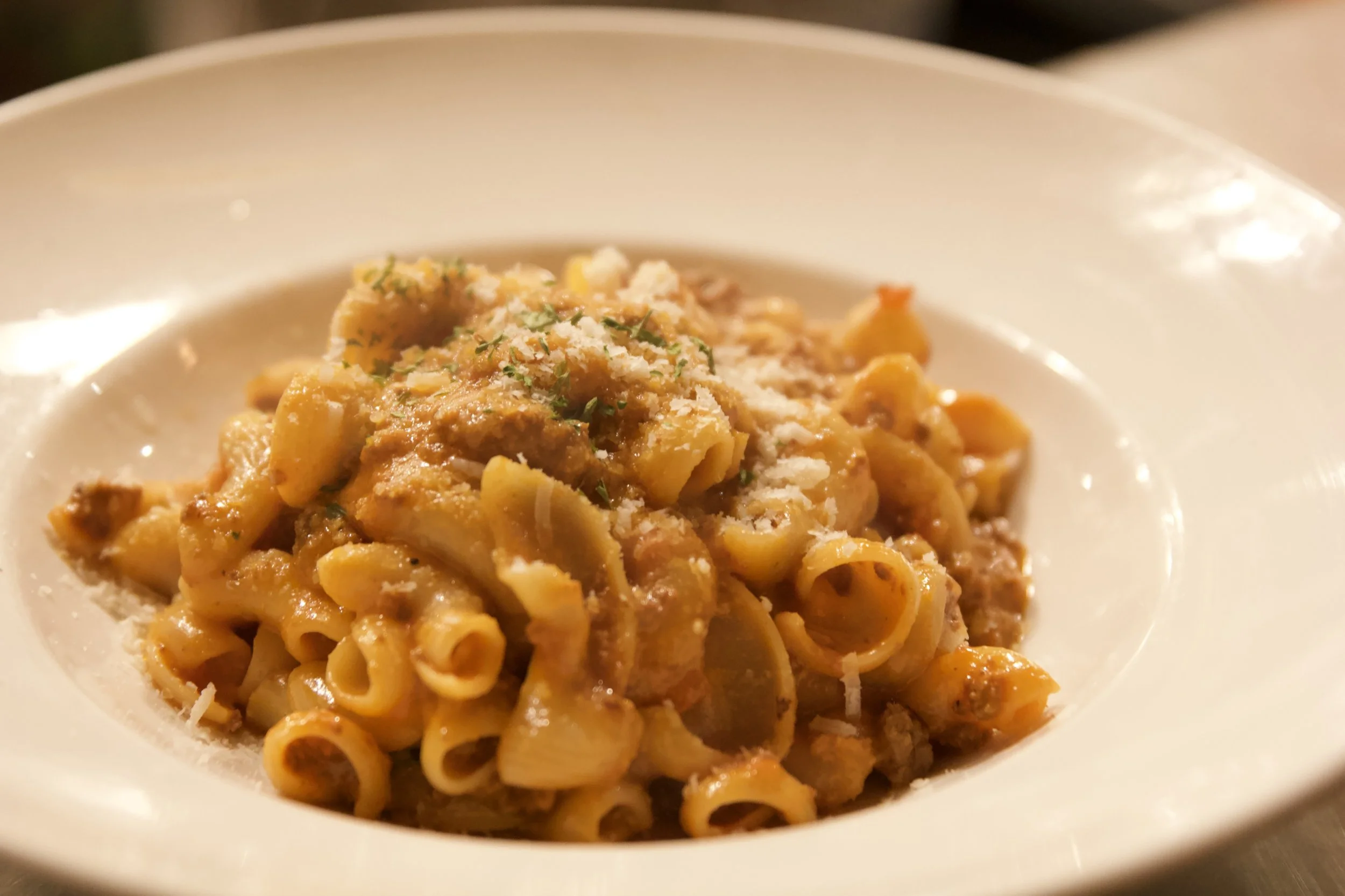 Plate of pasta with tomato sauce, grated cheese, and herbs.