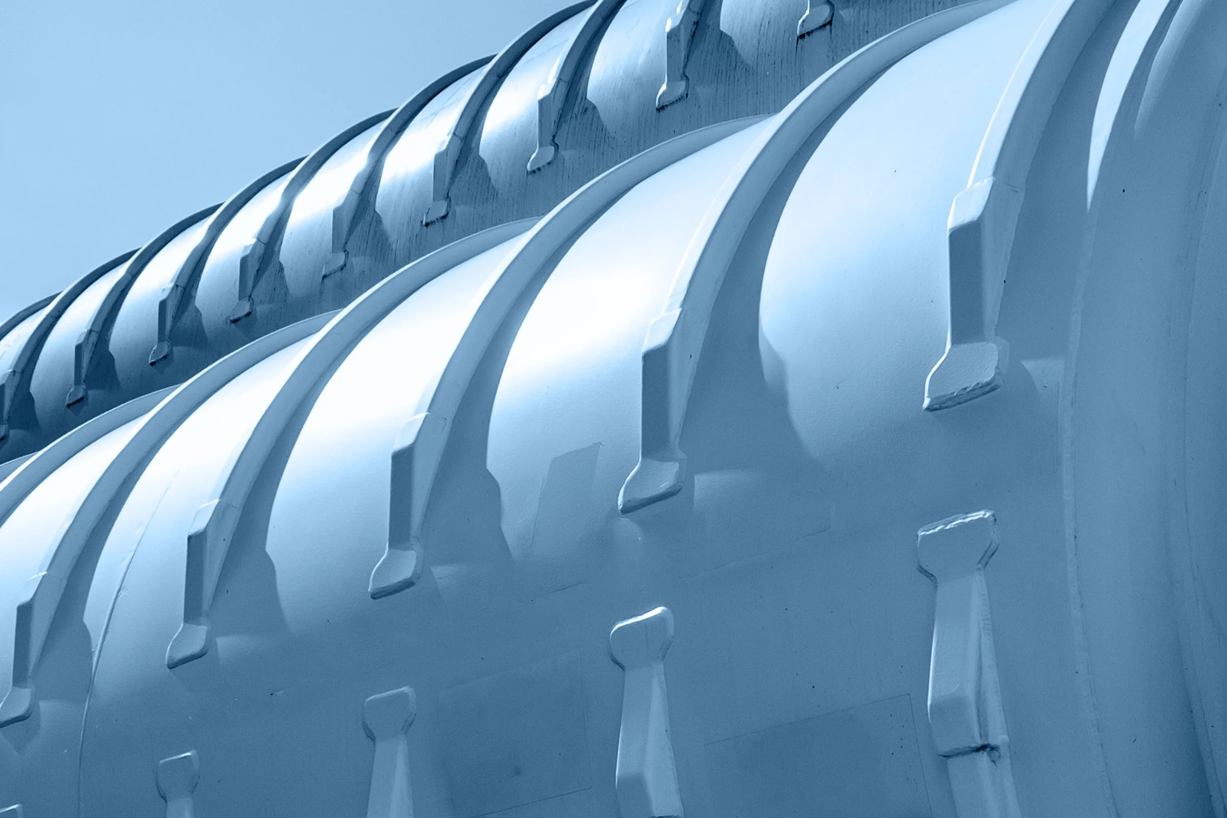 Close-up of a metallic turbine blade or fin with curved, evenly spaced blades.