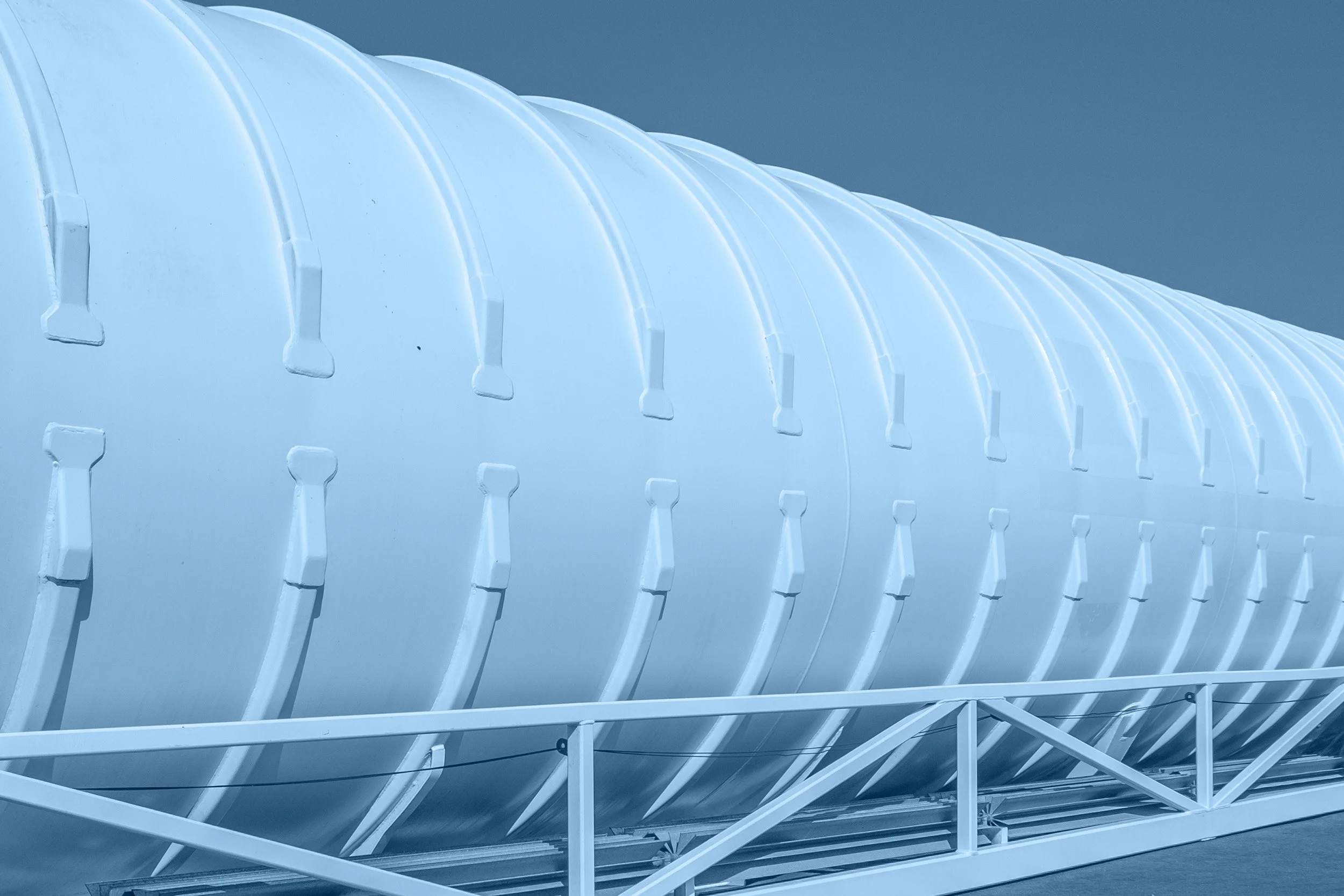 A large industrial structure with a curved, ribbed white exterior supported by a metal frame.