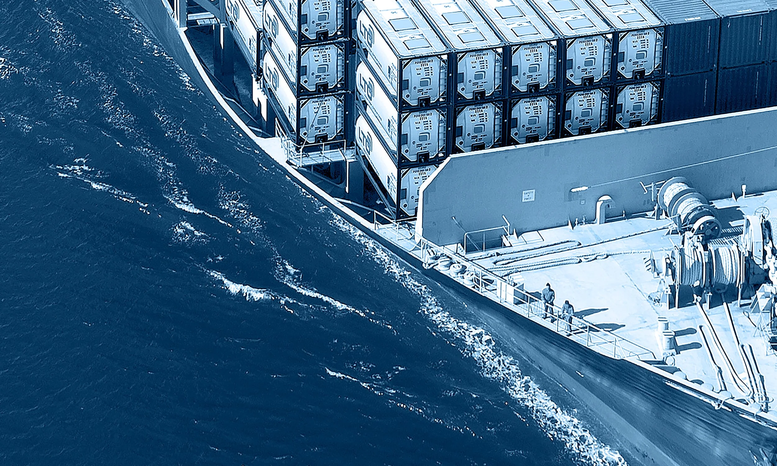 The image shows the side of a cruise ship or boat with a group of people walking on the deck, and large containers stacked on the boat, near the ocean.