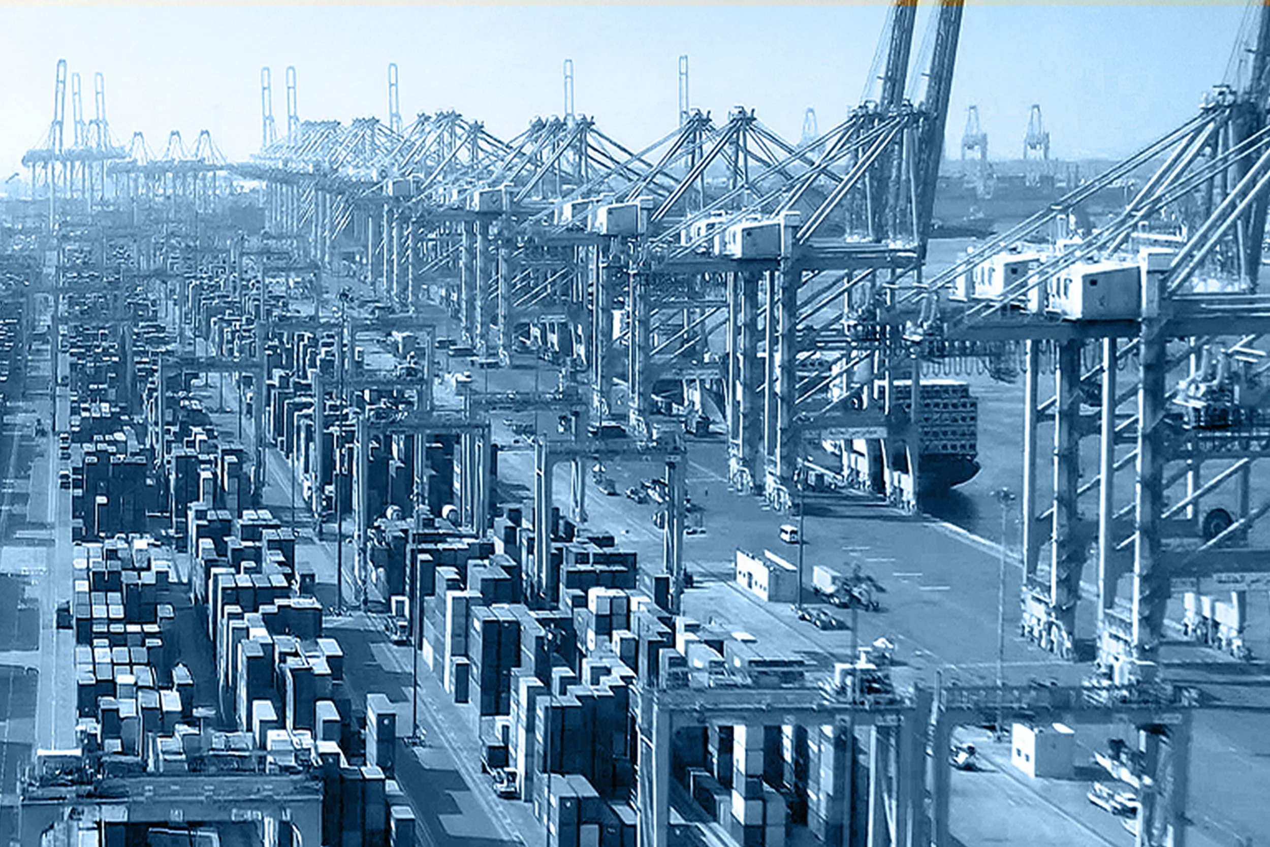 A large container ship docked at a busy port with numerous cranes lifting cargo containers.