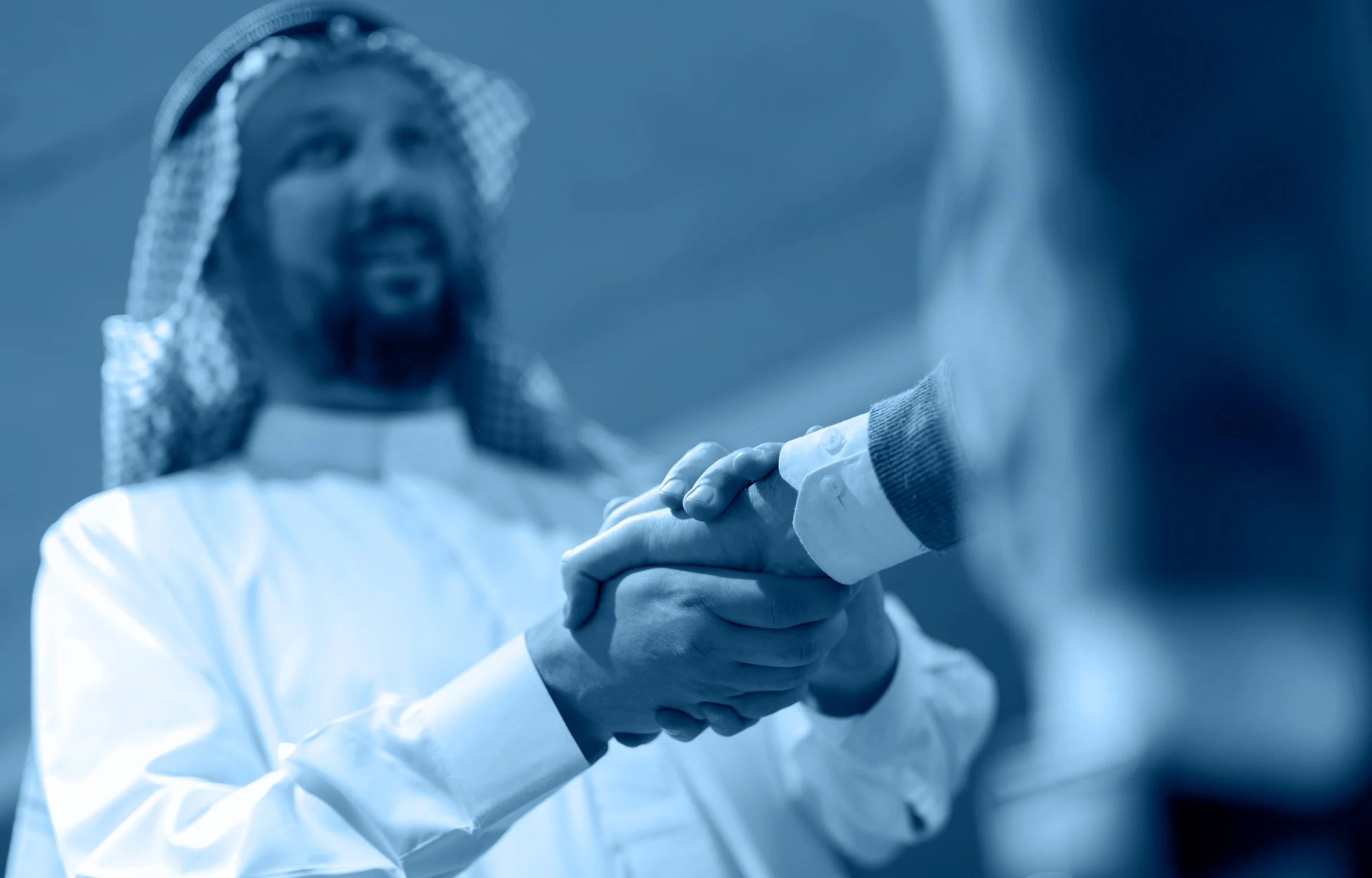 A person dressed in white and a person in casual clothing are holding hands, with one person's hand resting on top of the other's.