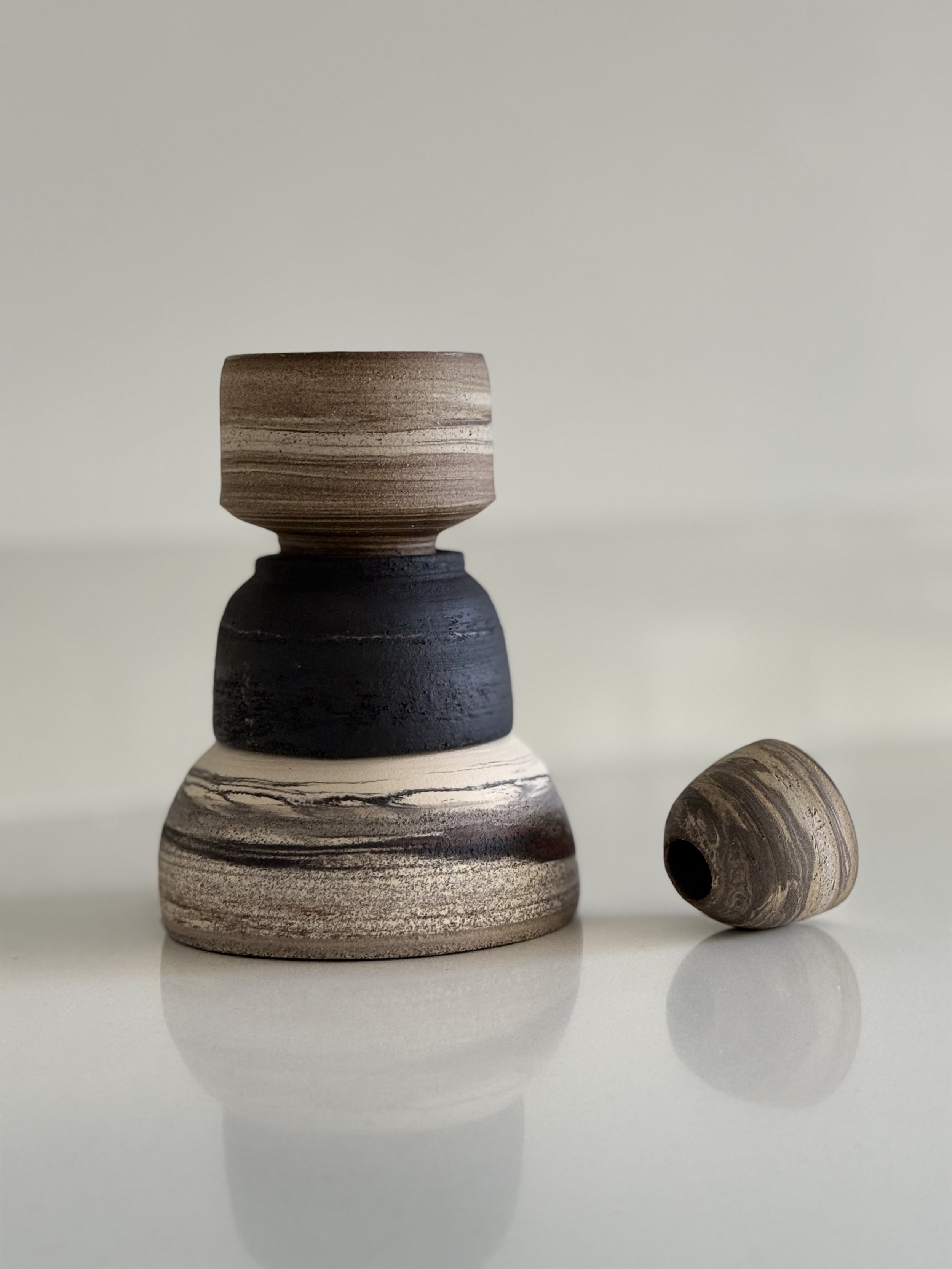 Stacked wooden bowls with a smaller wooden ring beside them on a reflective surface.