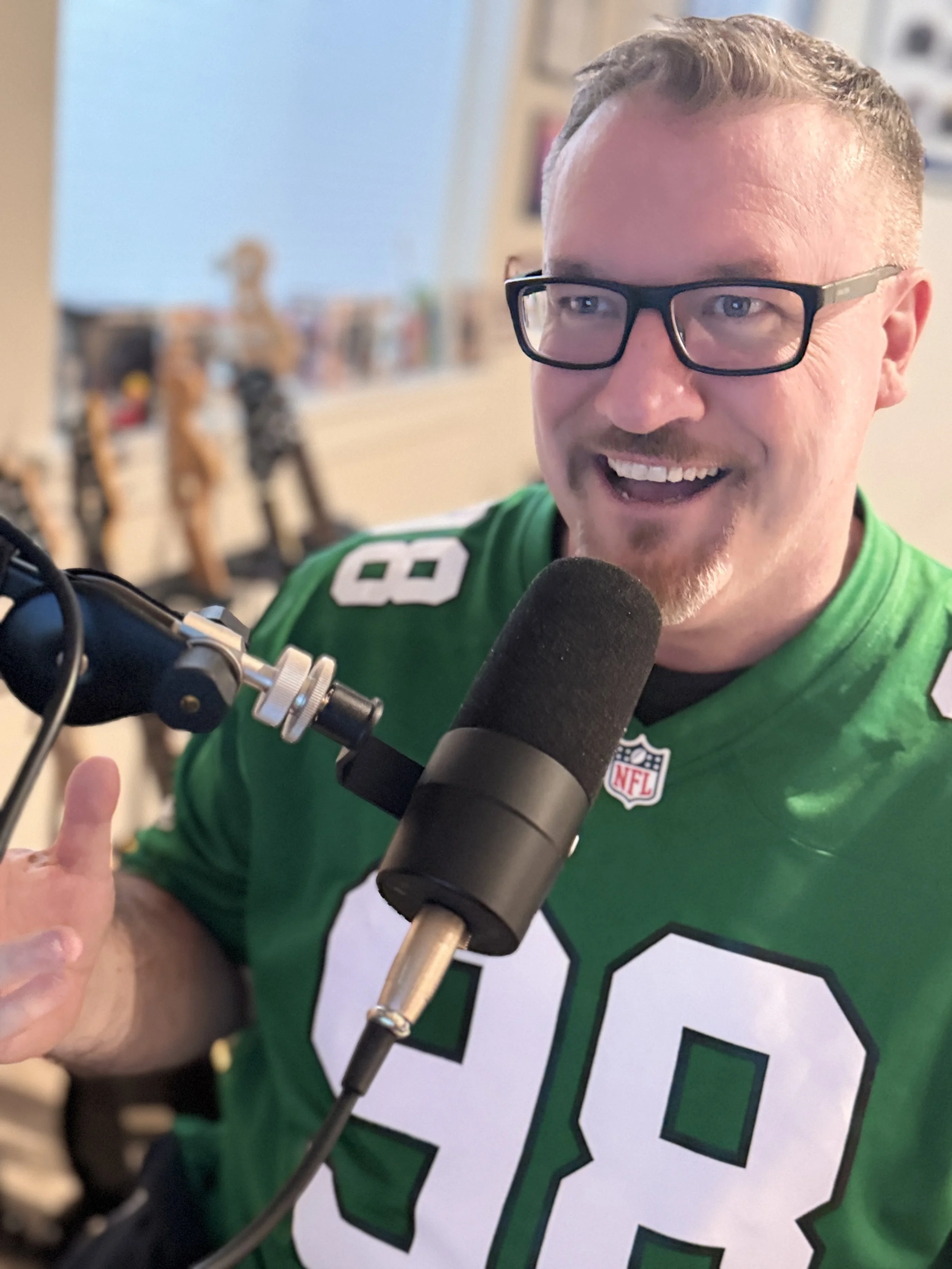 Jeff wearing a jersey and speaking into a podcast microphone.