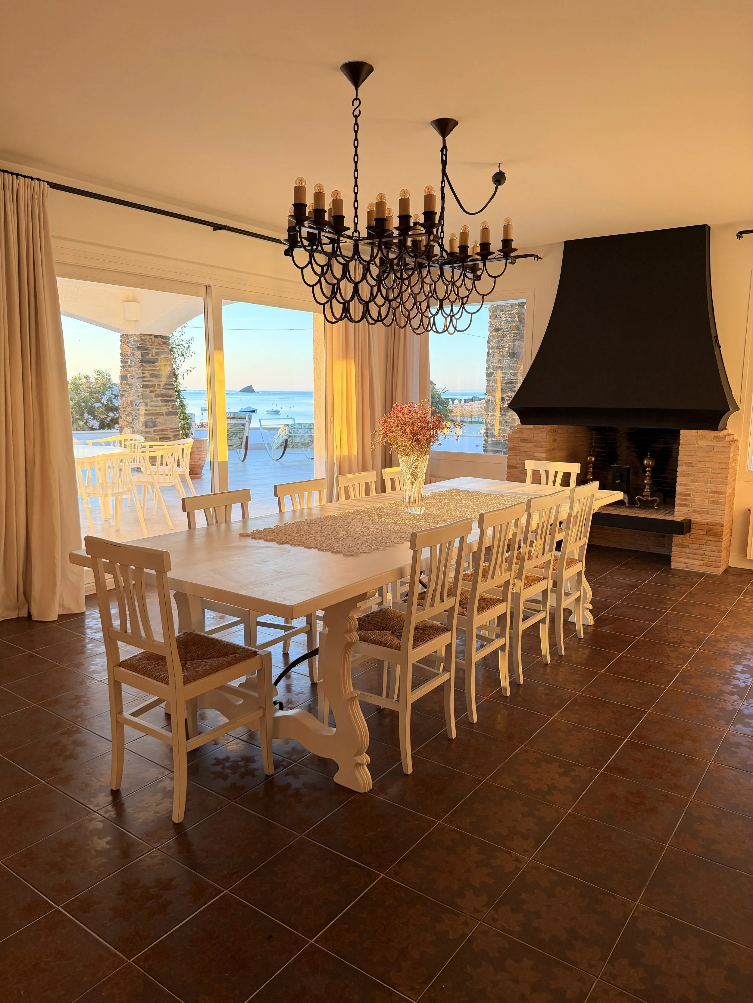 Amplio comedor con una gran mesa blanca ycon magníficas vistas al mar desde todas sus ventanas en la casa de alquiler Ca la Nuri - Cadaqués 