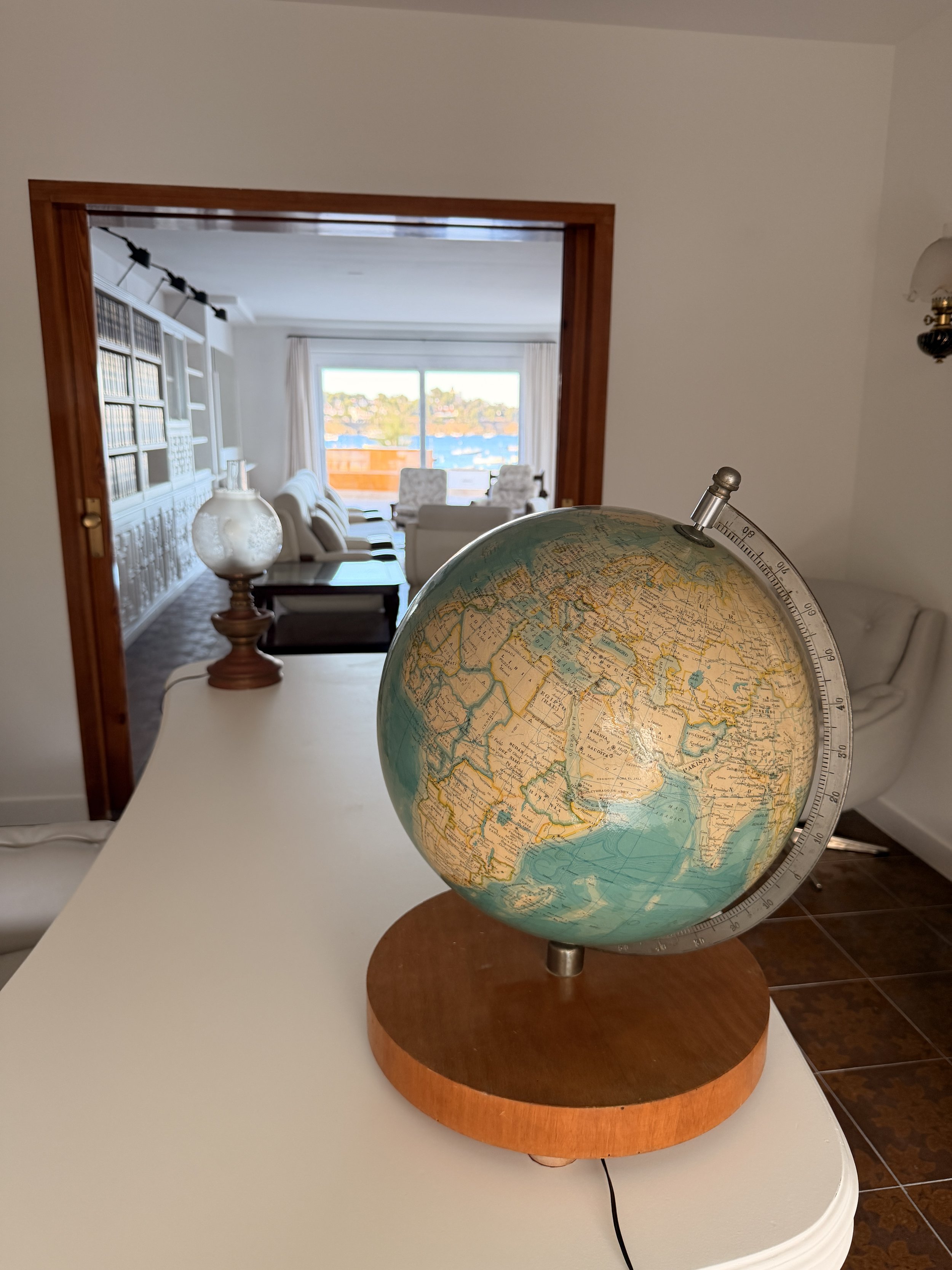 Despatxo con vistas al mar en la Casa de alquiler Ca la Nuri - Cadaqués. Un espacio luminoso, cómodo.  Con acceso y vistas al jardín interior. Un espacio donde trabajar relajado. Globo terráqueo en primer plano. 