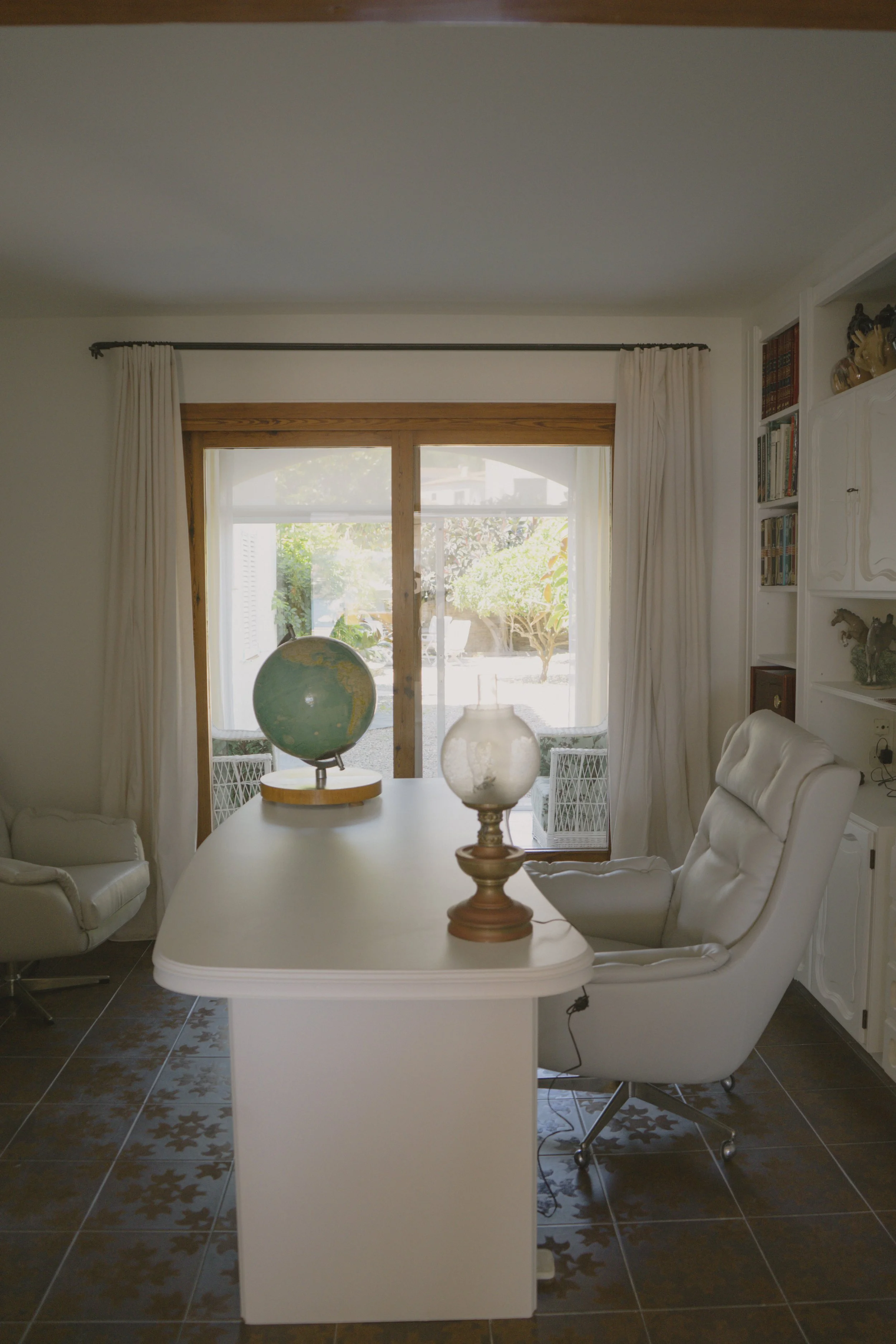 Despatxo en la Casa de alquiler Ca la Nuri - Cadaqués. Un espacio luminoso, cómodo, con acceso a la sala de estar - comedor, y a una pequeña galería. Con vistas al jardín interior. Un espacio donde trabajar relajado y con un ambiente cálido.