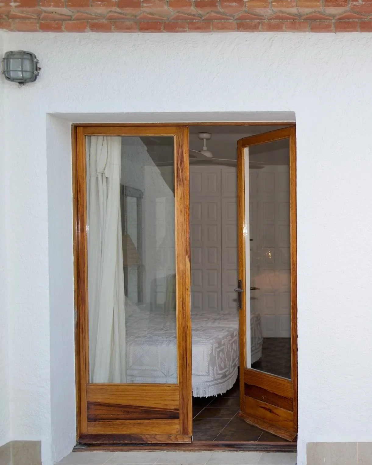 Habitación en la casa de alquiler Ca la Nuri Cadaqués. Habitación doble con terraza y vistas al mar. Tiene una terraza con vistas al mar. Decorada con cubrecama de ganchillo y lámparas de esparto. 