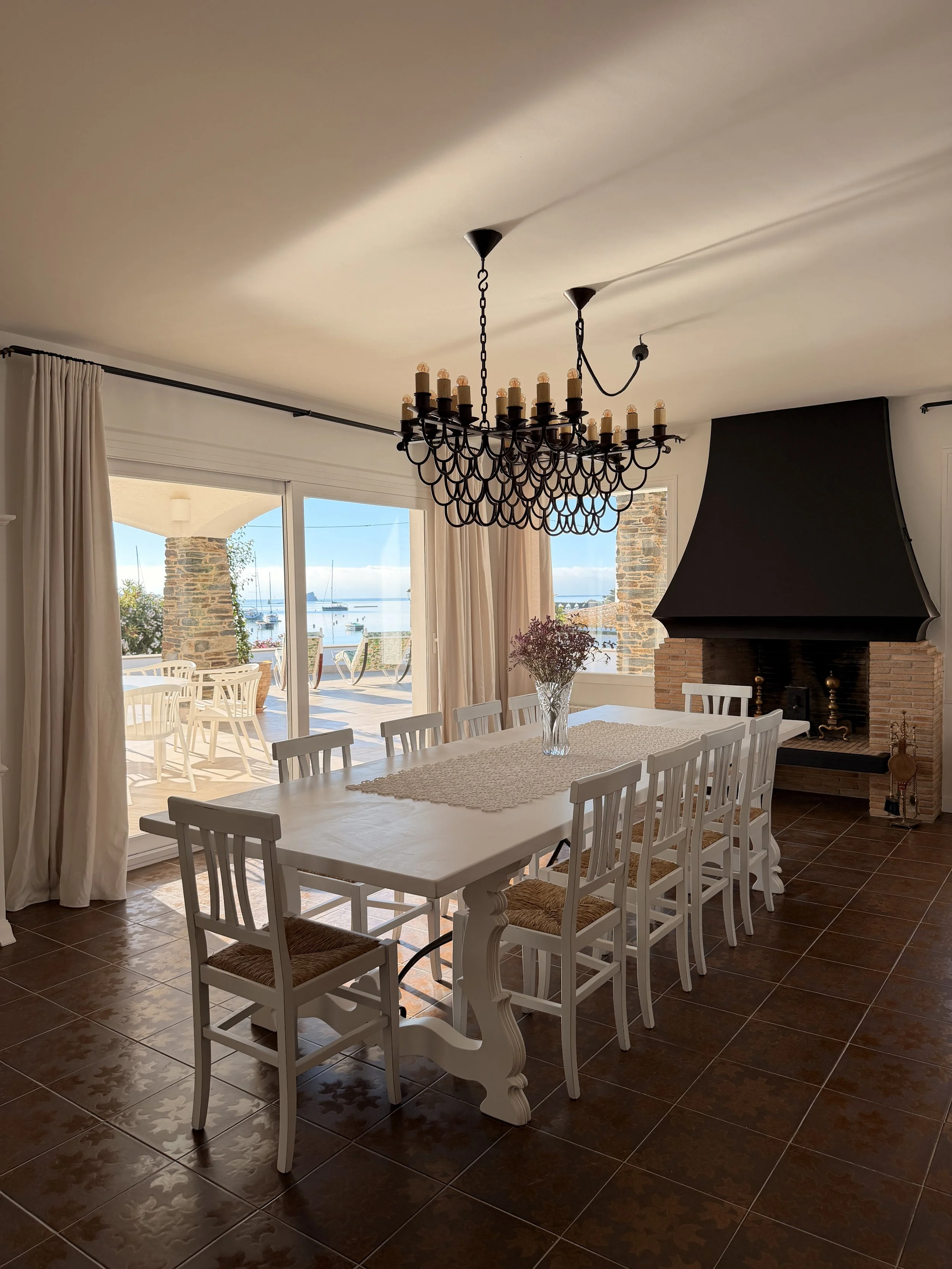 Amplio comedor con una gran mesa blanca ycon magníficas vistas al mar desde todas sus ventanas en la casa de alquiler Ca la Nuri - Cadaqués 
