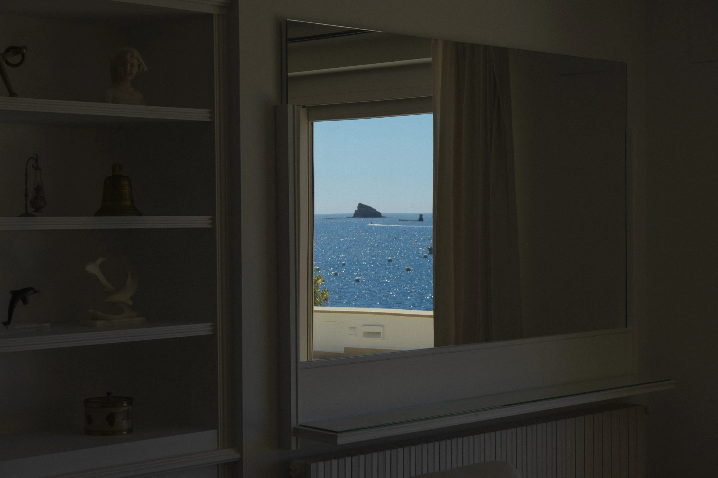 Espejo con reflejo del icónico islote de Cadaqués, Es Cucurucuc, en el magnífico comedor con vistas al mar en la exclusiva casa de alquiler Ca la Nuri