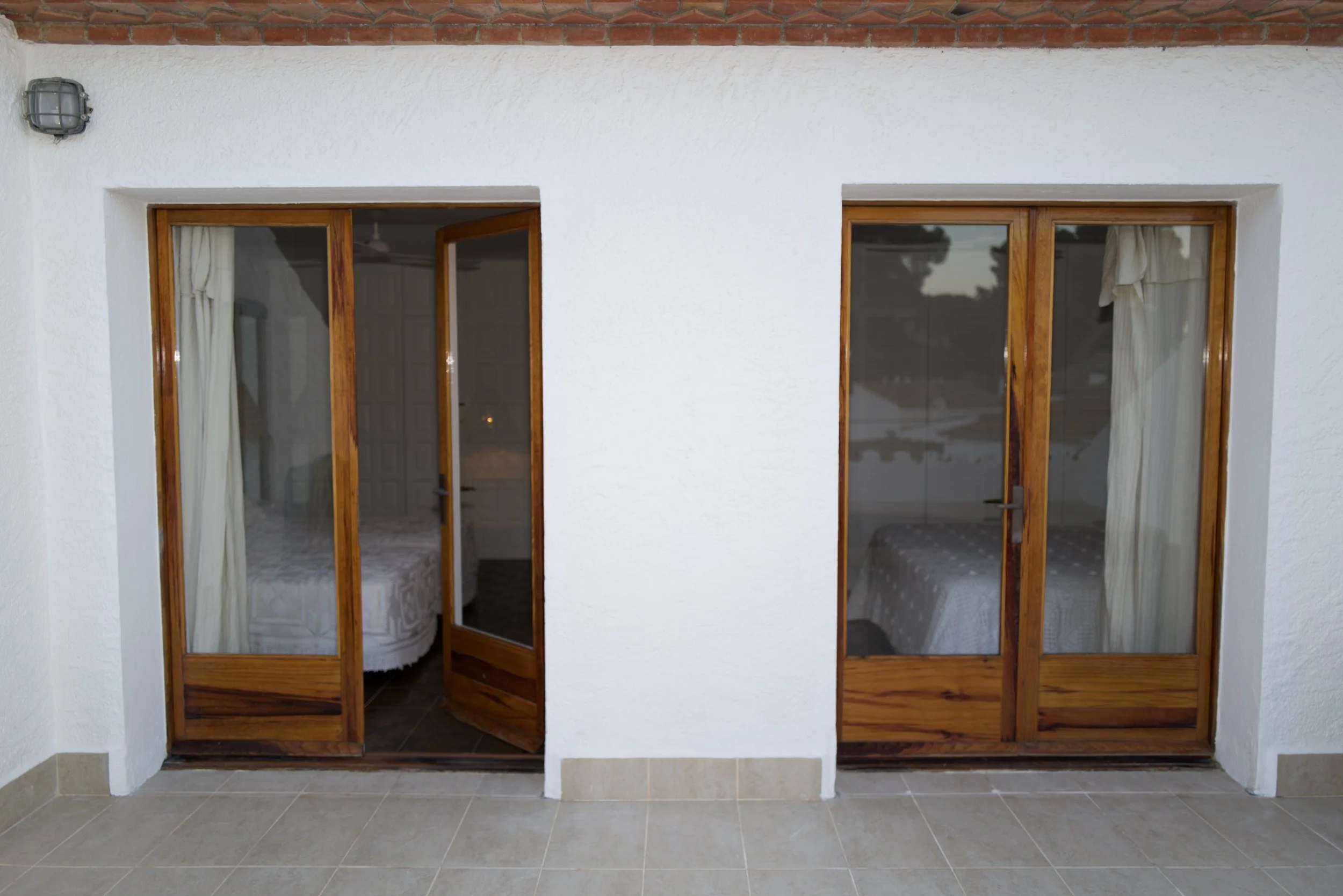 Habitación doble exclusiva en la casa de alquiler a primera linea de mar. Ca la Nuri Cadaqués. Dispone de una terraza con vistas a la montaña y al mar. Decorada con cubrecama artesanal de ganchillo y lámparas de esparto. 