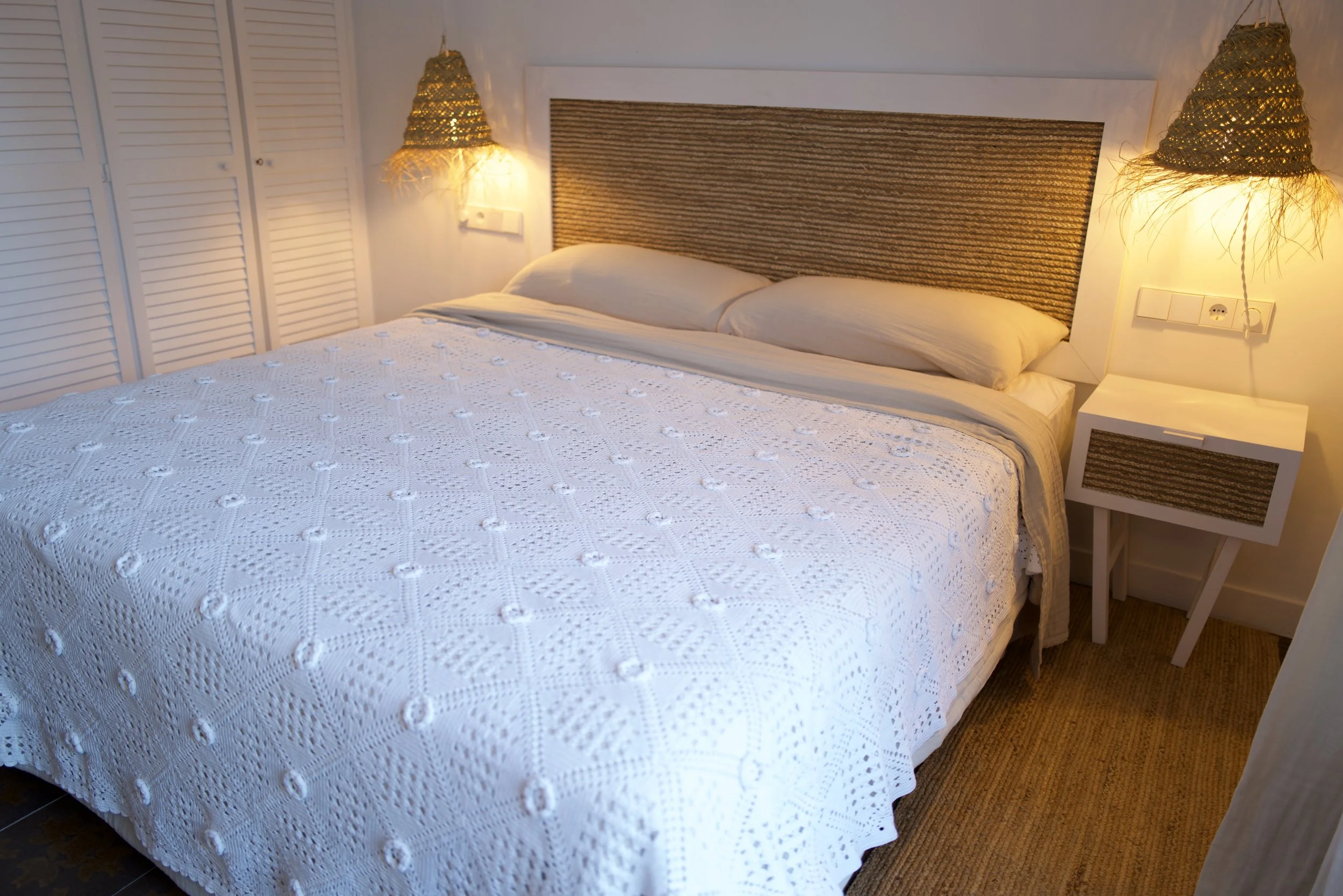 Habitación doble exclusiva en la casa de alquiler a primera linea de mar Ca la Nuri Cadaqués. Dispone de una terraza con vistas a la montaña y al mar. Decorada con cubrecama artesanal de ganchillo y lámparas de esparto. 
