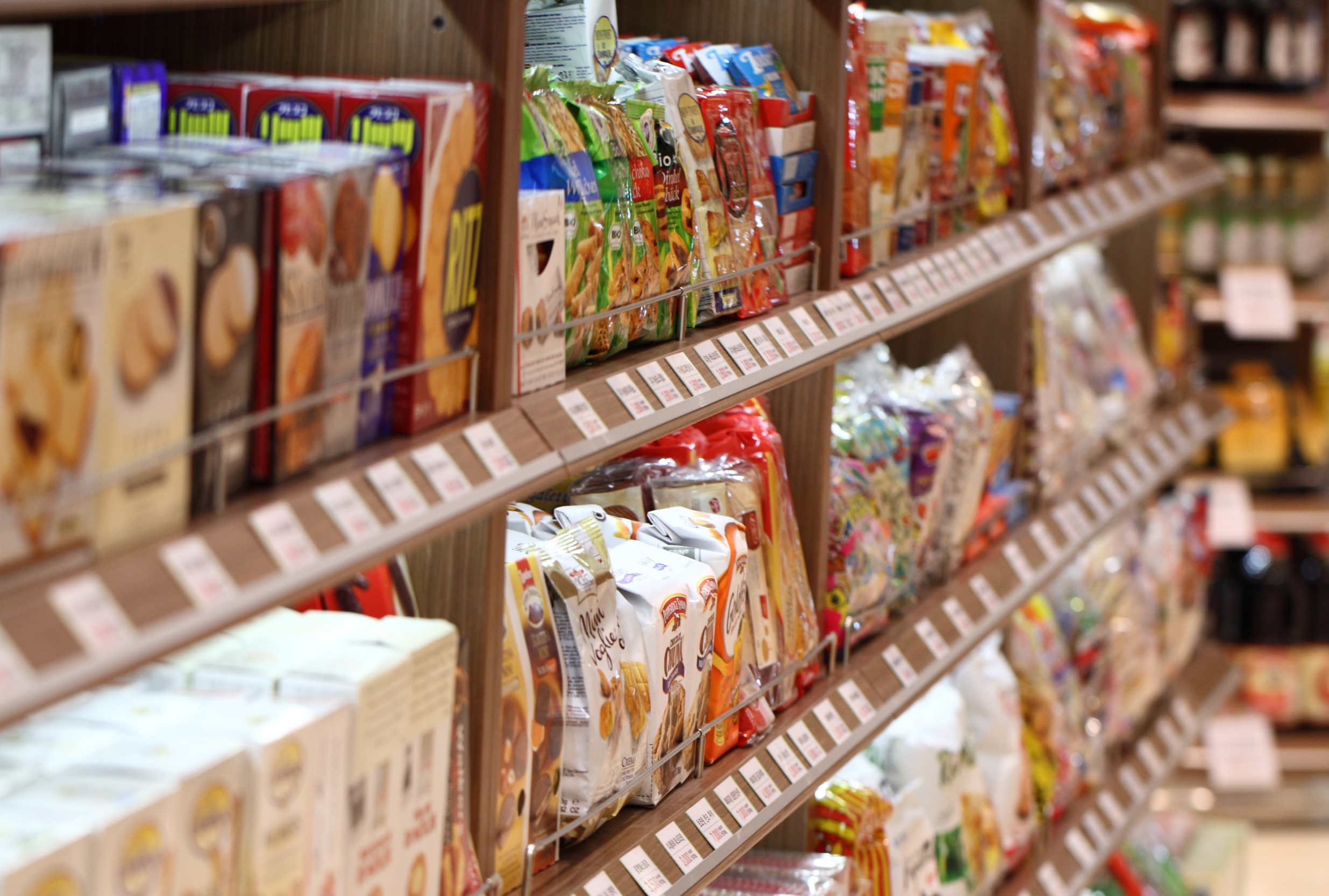 Shelves stocked with various packaged snack foods and candies in a grocery store.
