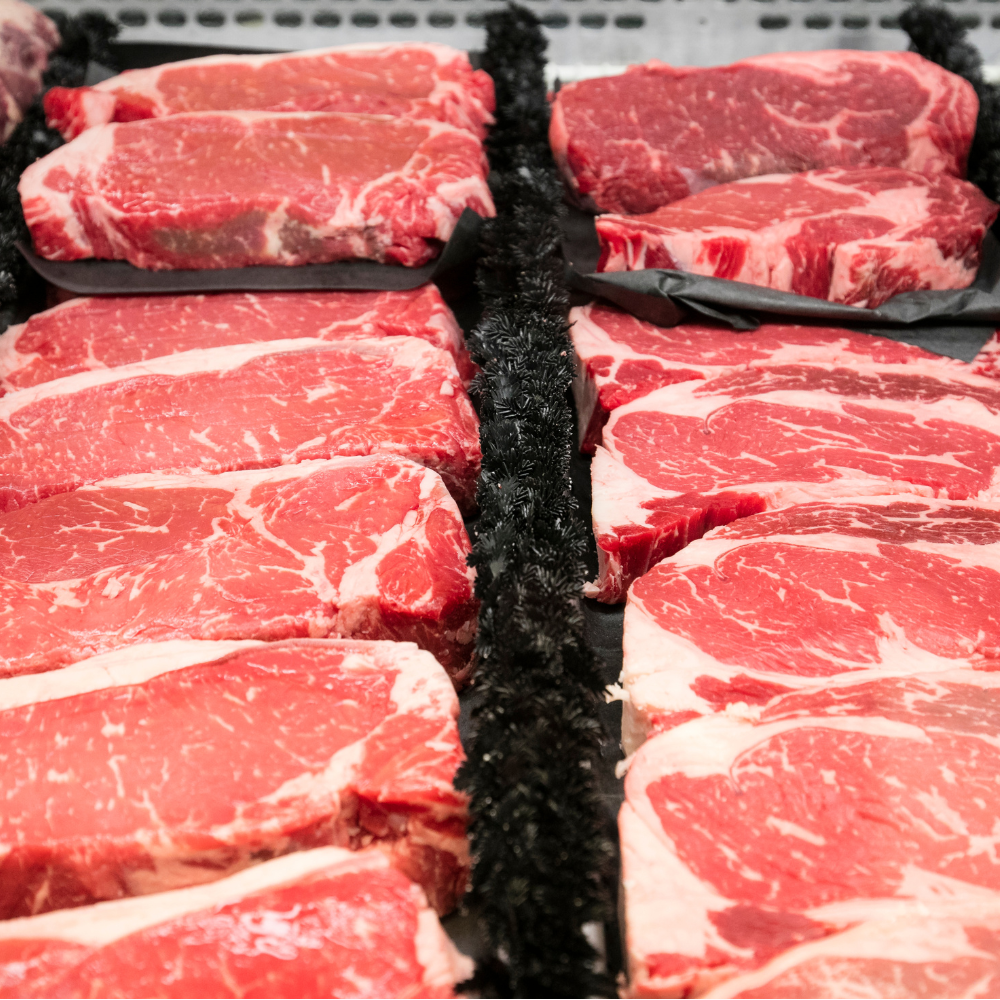 Various cuts of raw beef steak arranged on display at a butcher's shop or grocery store.