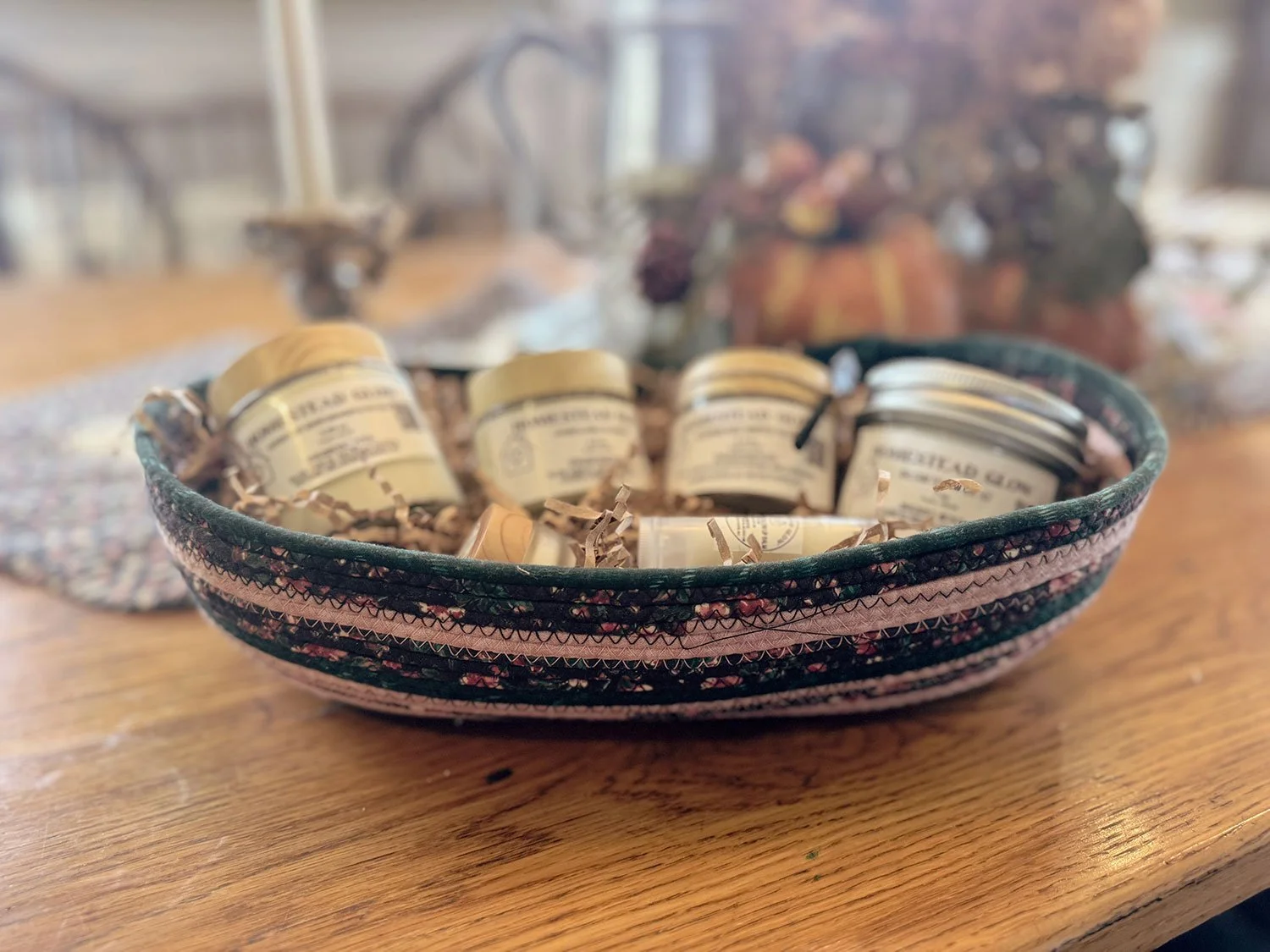 A decorative bowl containing small jars with vintage-style labels, filled with a substance, on a wooden table.