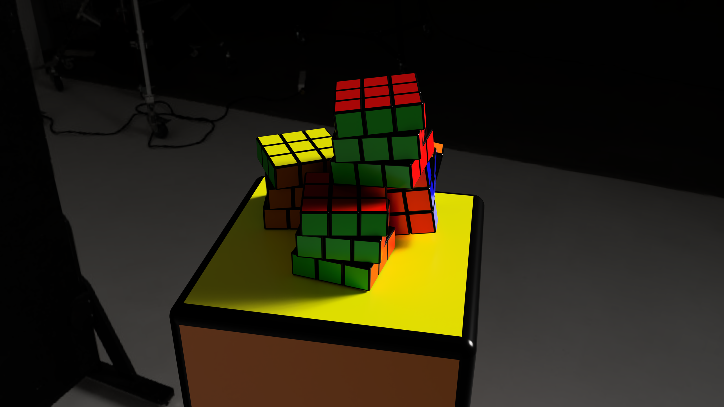 A table with multiple Rubik's cubes in various states of solved, positioned on top of a yellow and black surface.