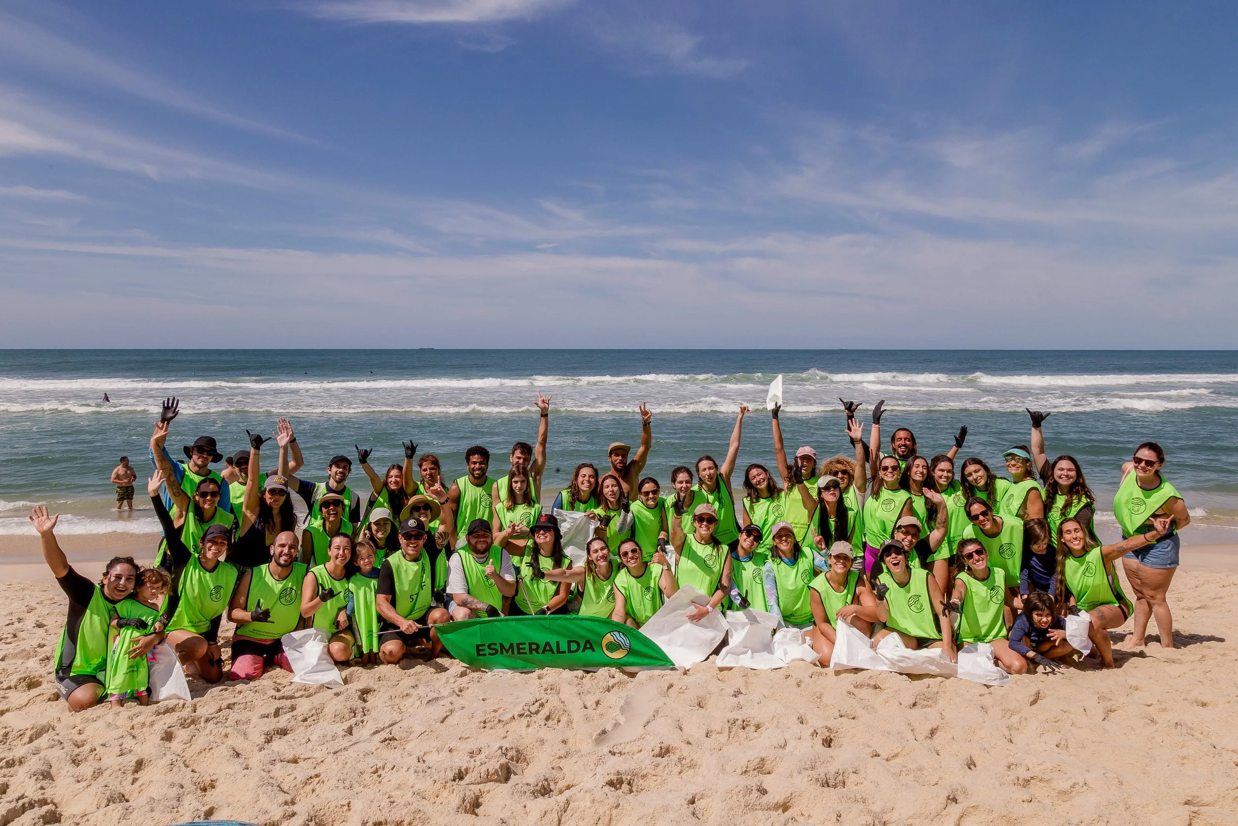 Grupo de pessoas voluntárias fazendo uma limpeza de praia - Onda Verde