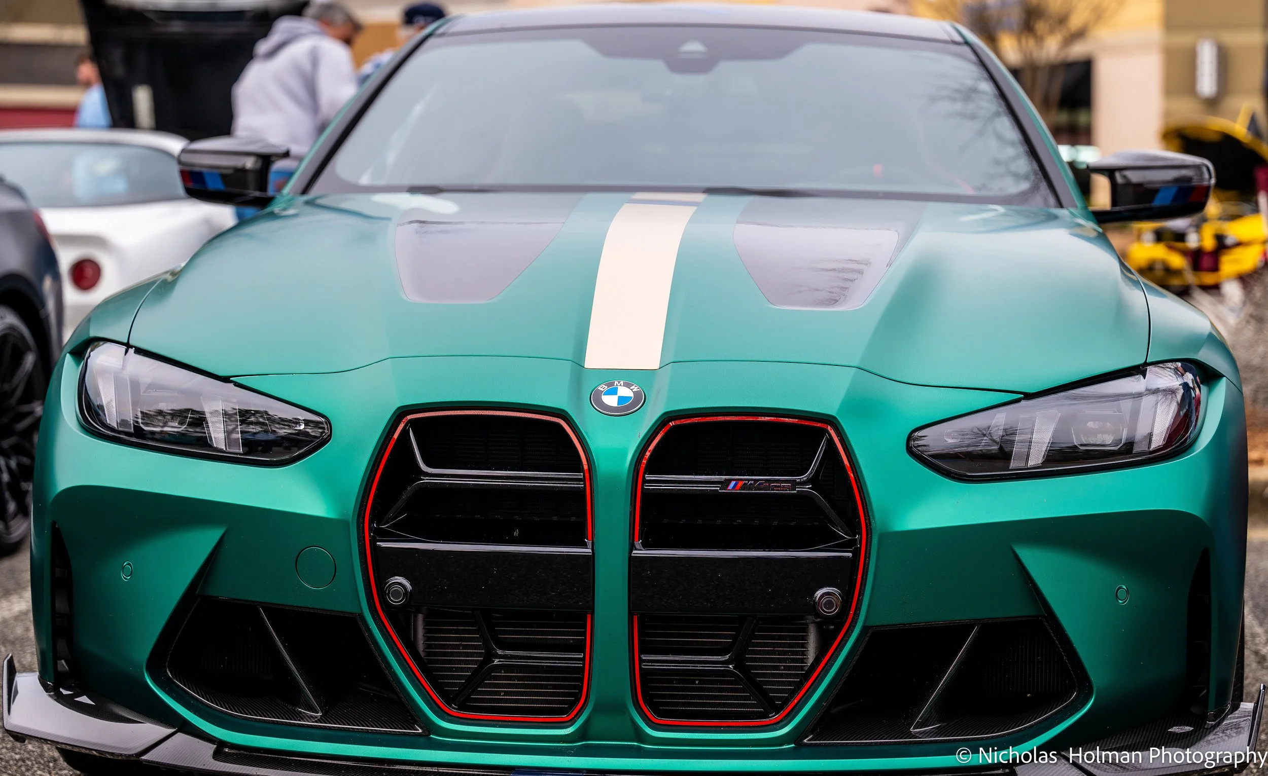 Front view of a green BMW racing car with black and red accents, parked outdoors.