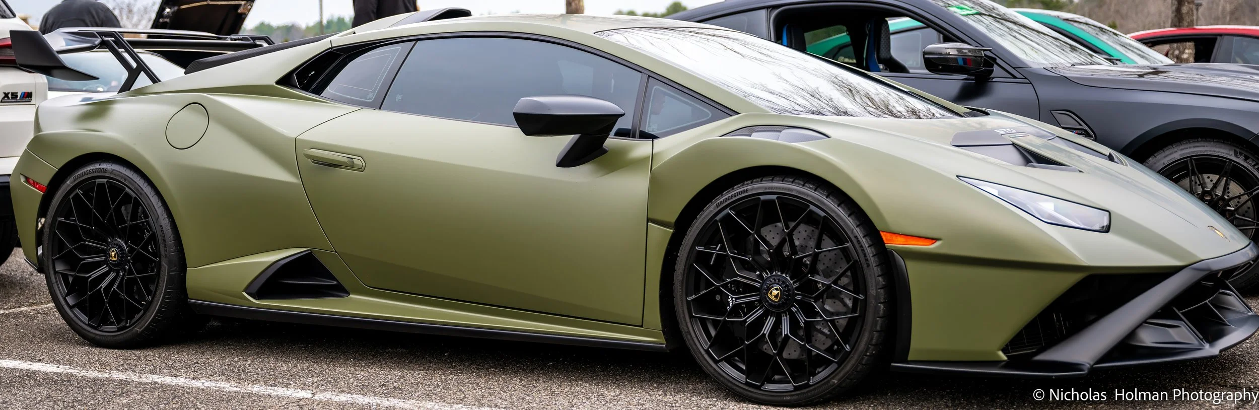 A green Lamborghini sports car parked among other vehicles outdoors.
