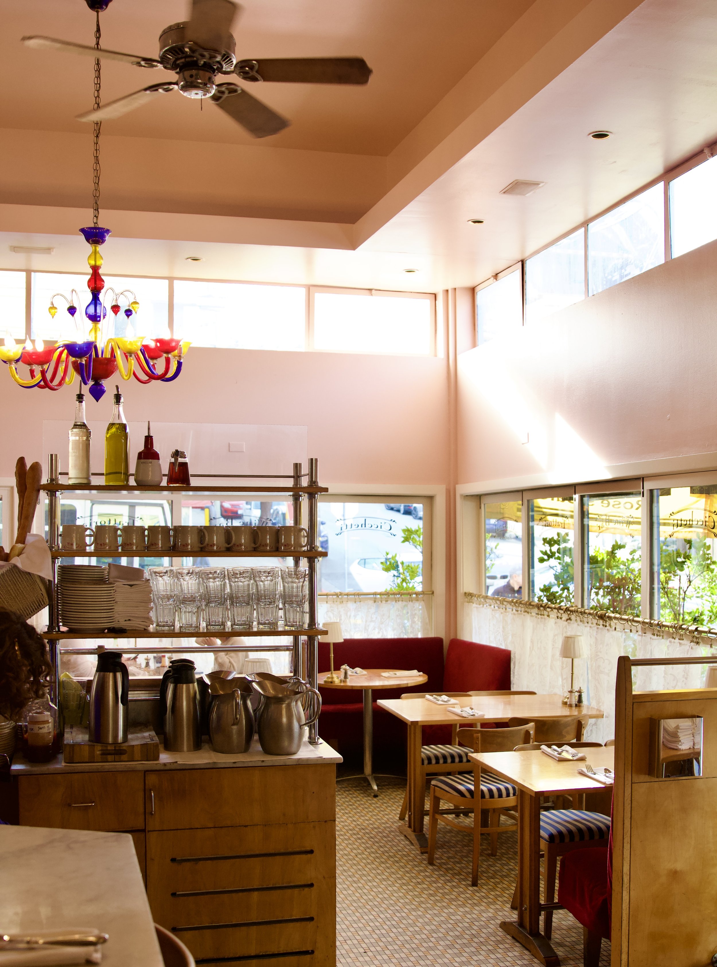 Inside Rose's Cafe with colorful pink walls, natural light, intimate tables and velvet booths