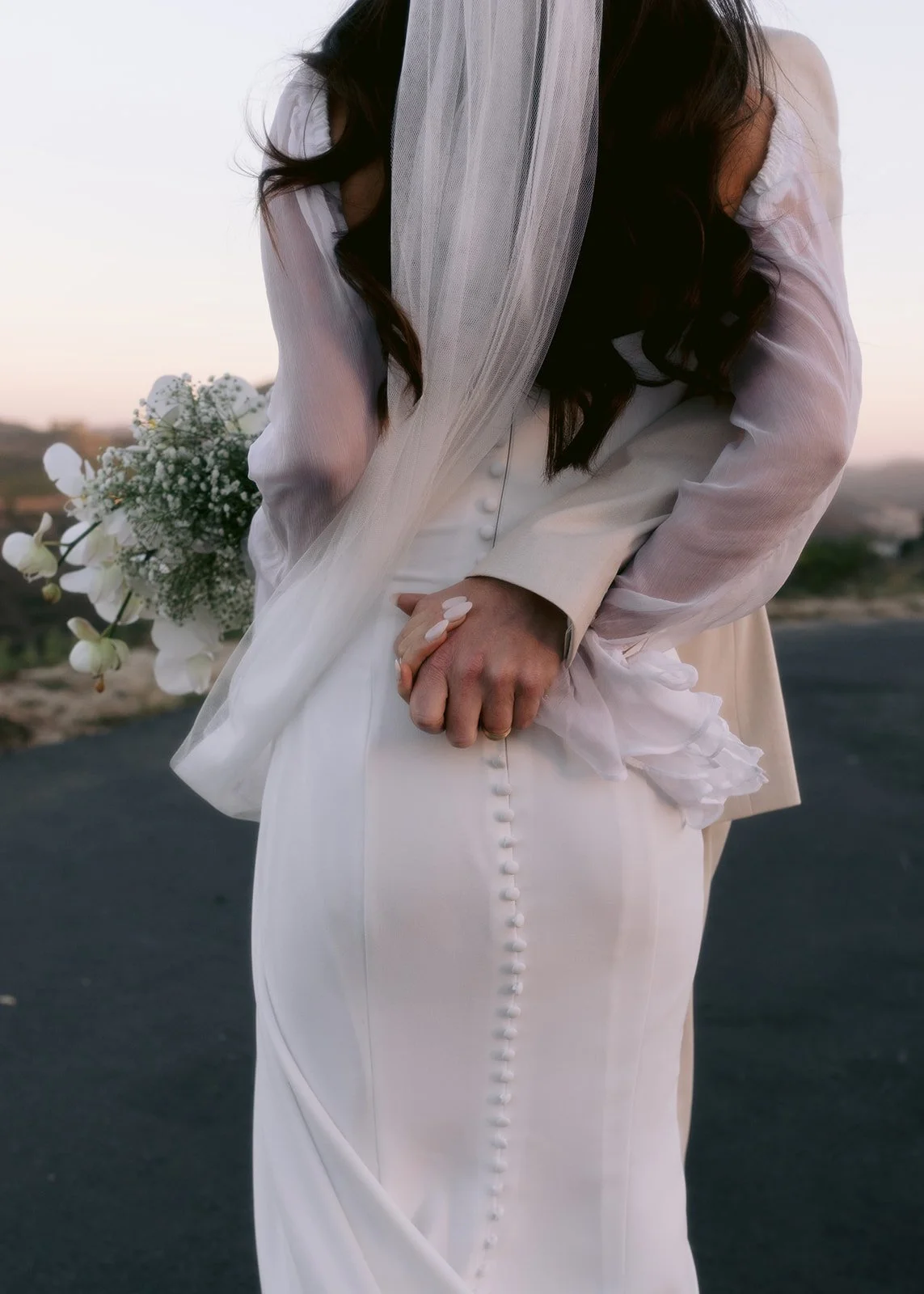 Elegant veil detail photo of bride and groom holding hands.