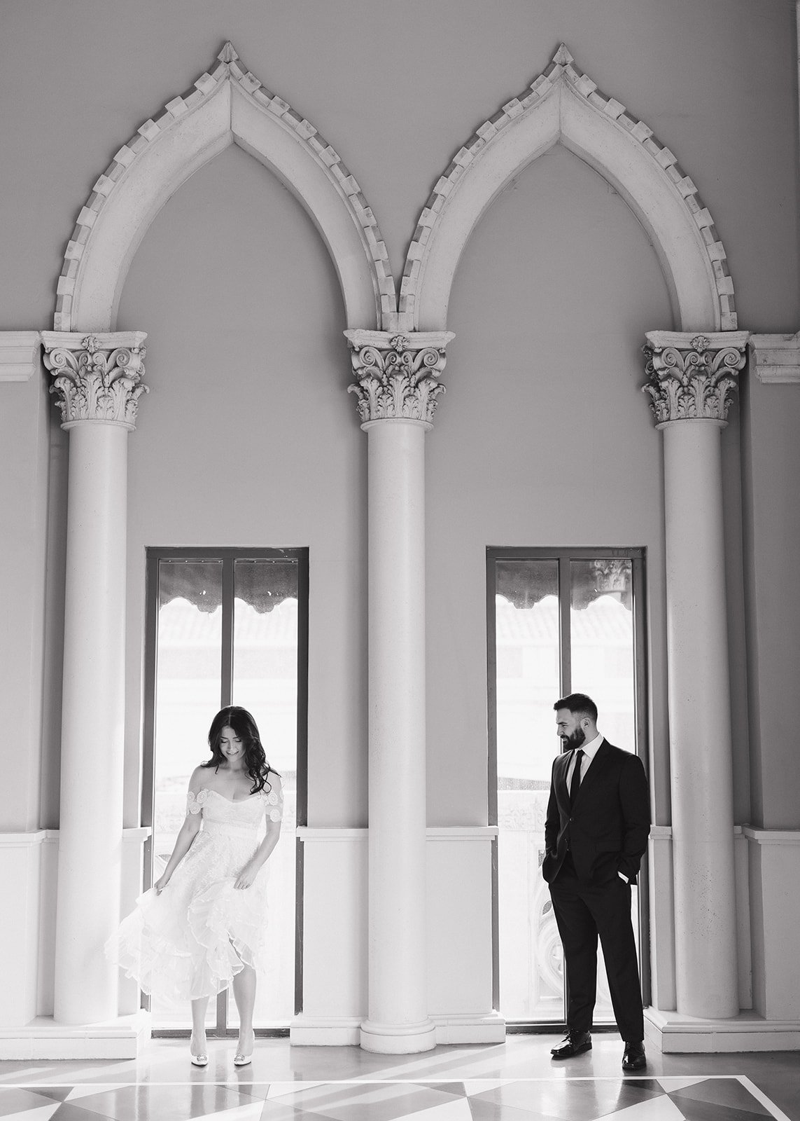 Architectural engagement portrait framed by symmetrical structural lines.