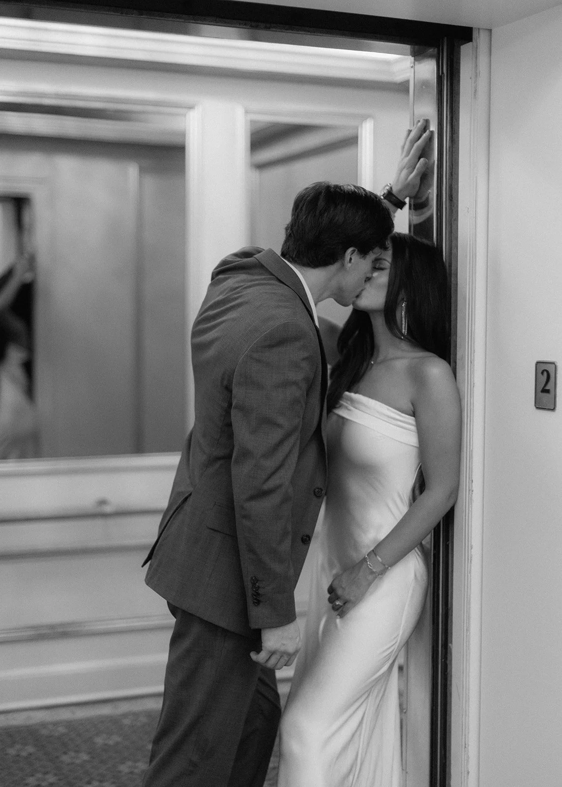 Couple posed inside elevator during elegant engagement portrait.