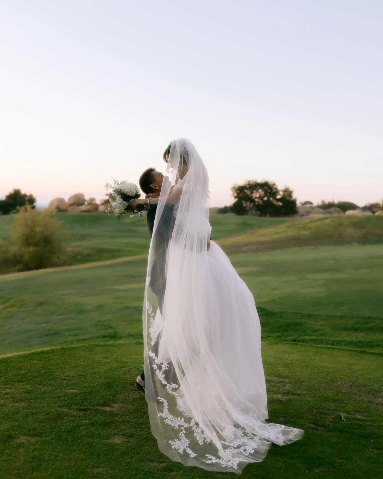 Groom lifts bride for portrait at country club wedding.