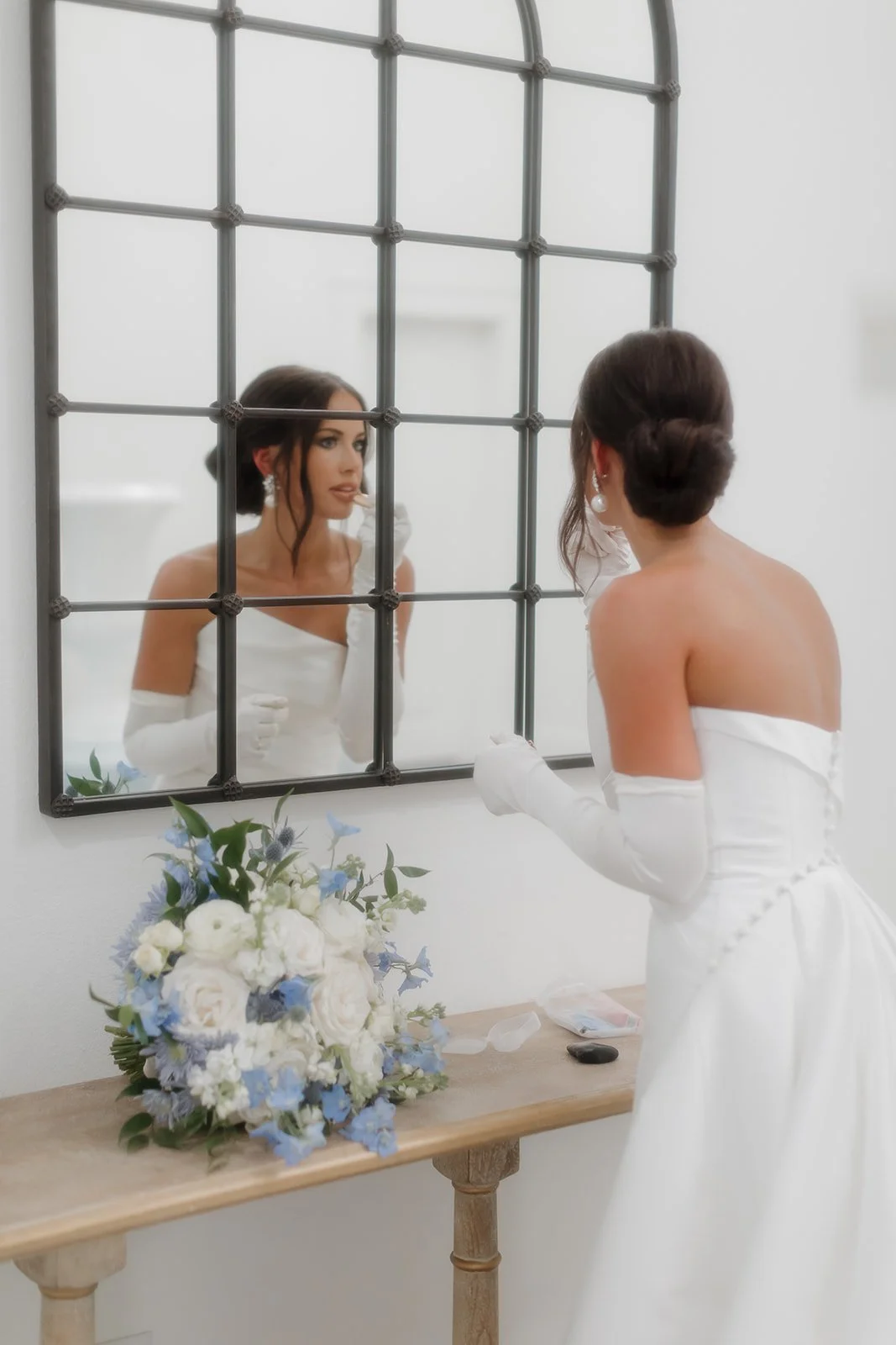 Modern, fine art bridal moment captured as bride applies her makeup.