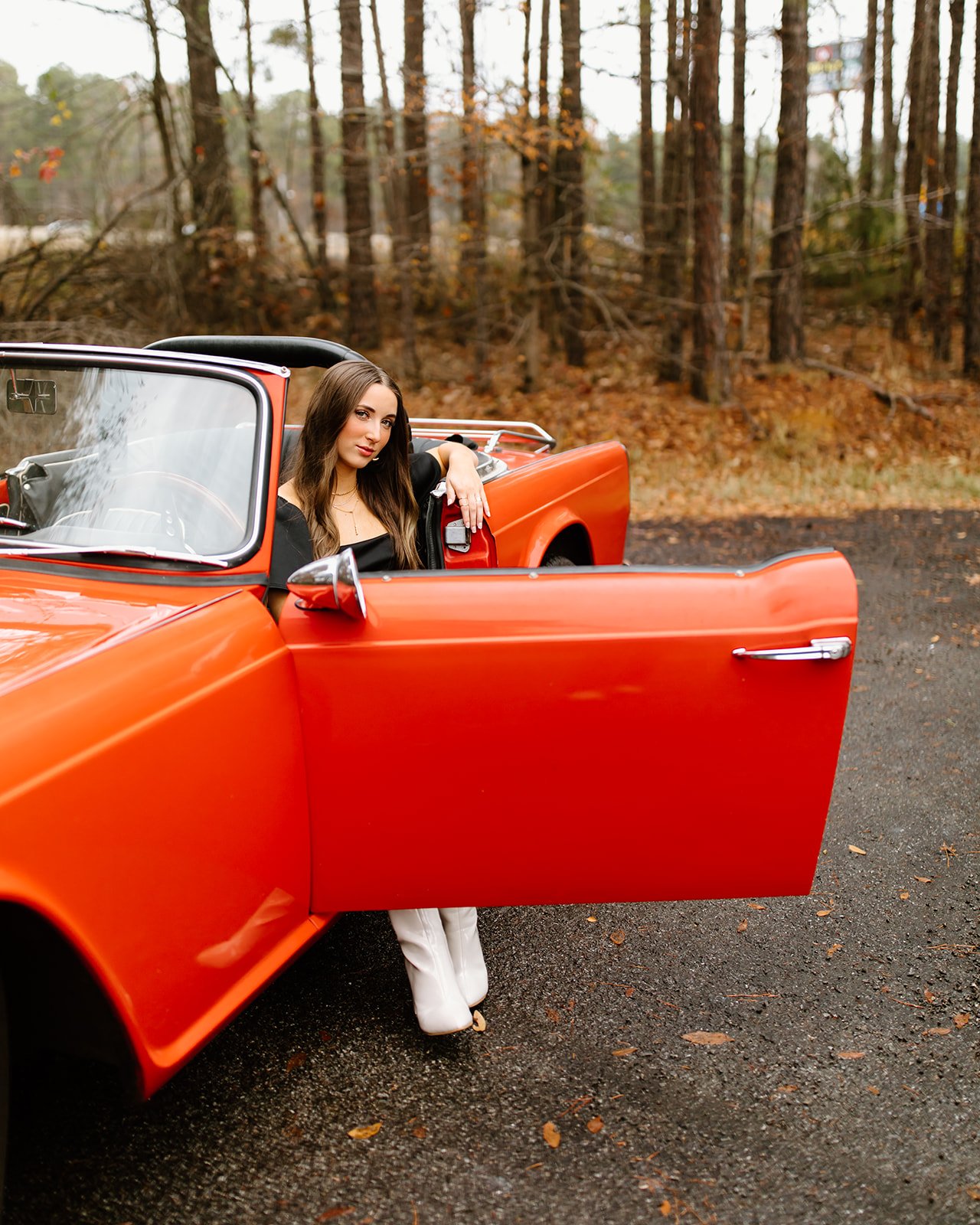 Senior portrait posed beside classic car in natural light.