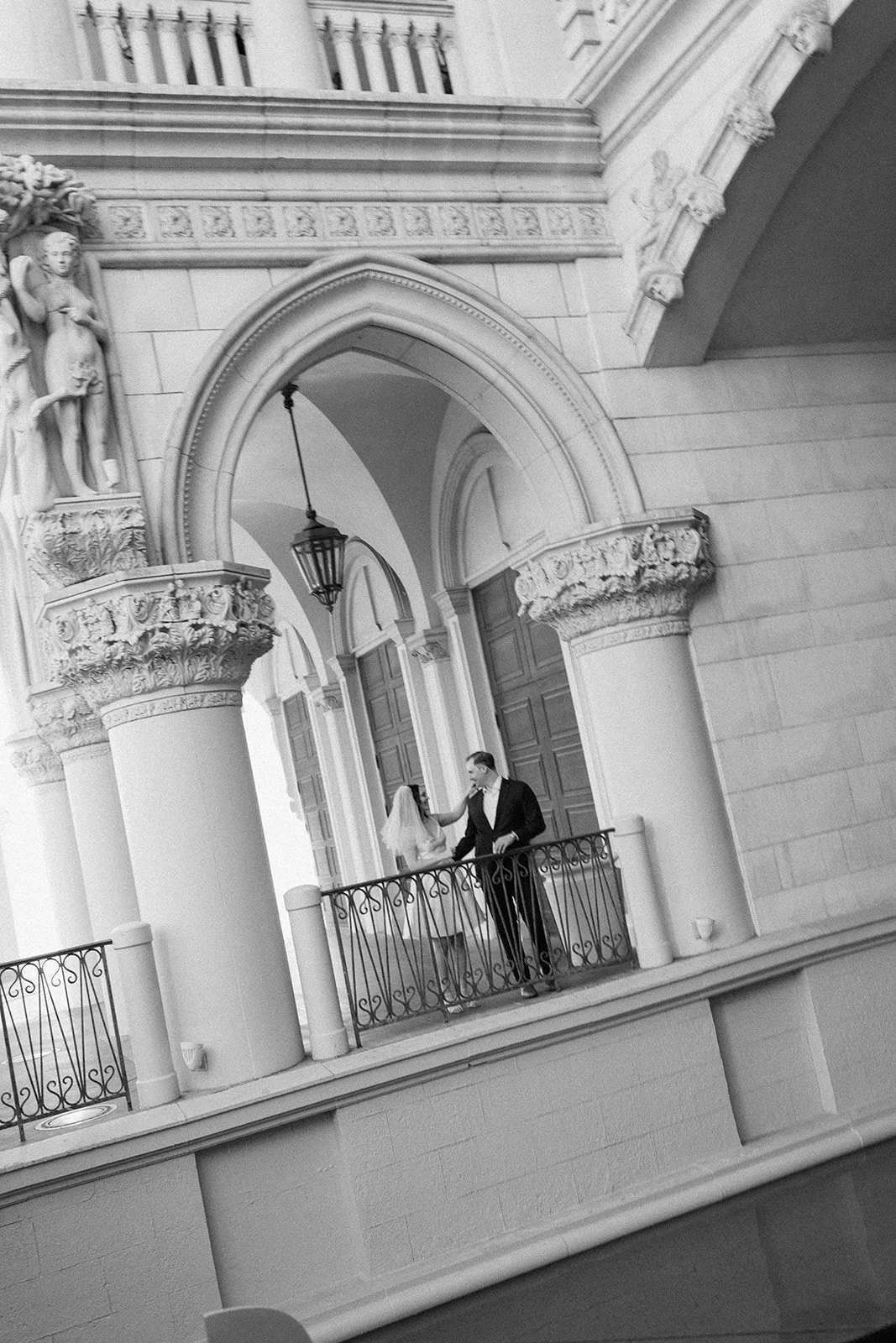 Bride and groom centered within symmetrical architectural backdrop.