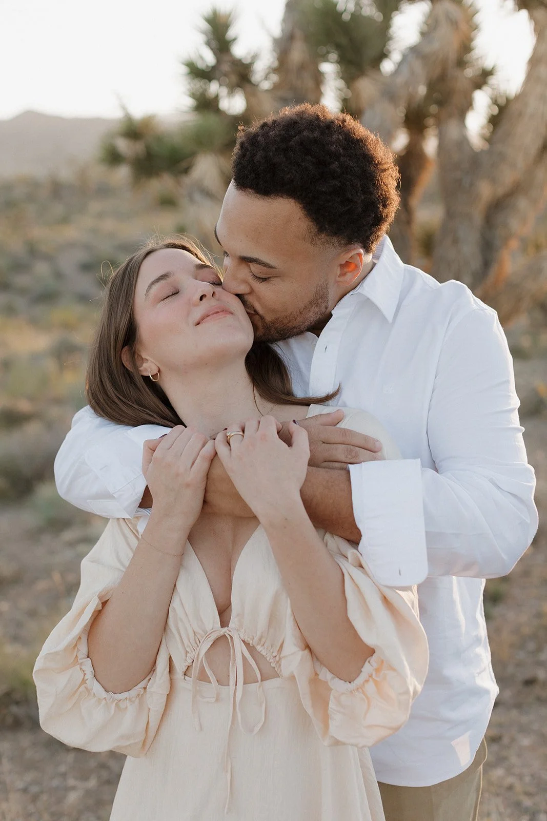 Couple embracing during sunset engagement session outdoors.