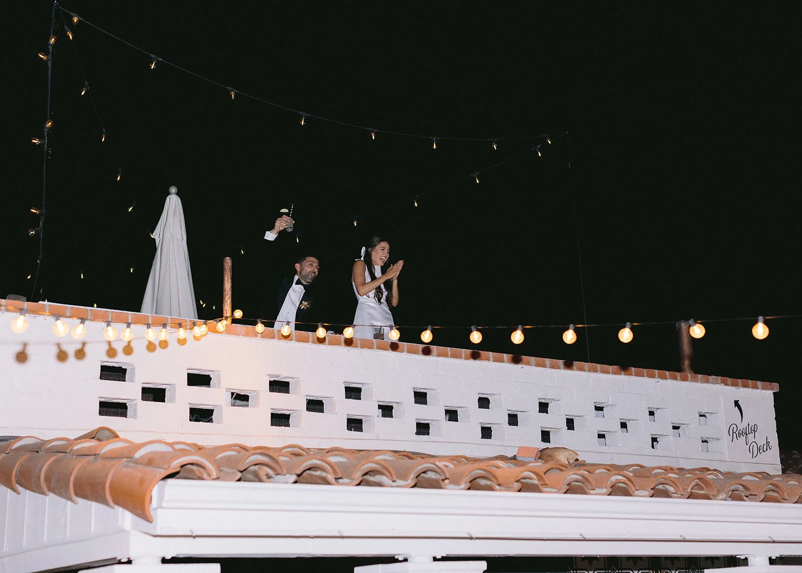 Bride and groom celebrate from balcony during their reception.