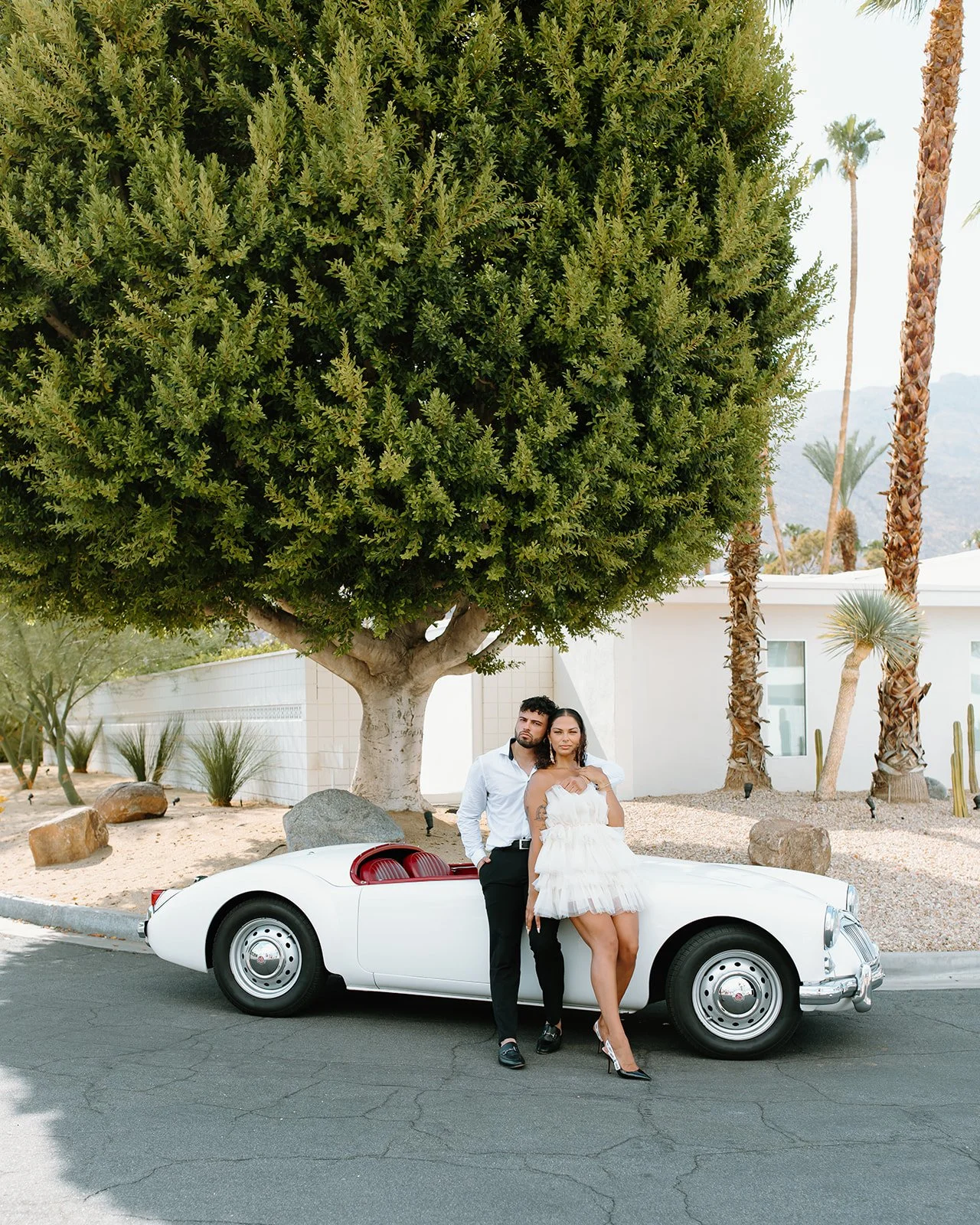 Couple posing with classic car at editorial photoshoot.