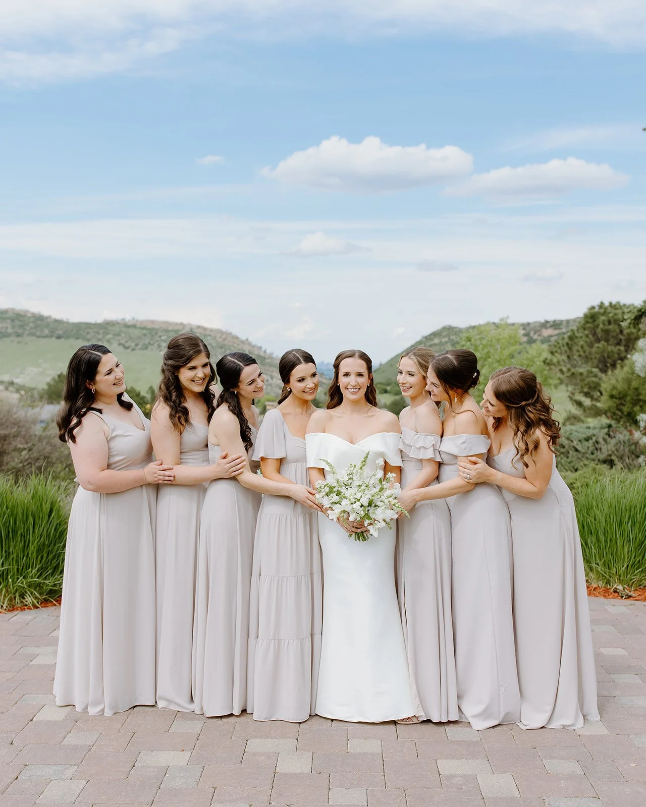 Bride shares a candid moment with her bridesmaids in their matching dusty rose dresses.