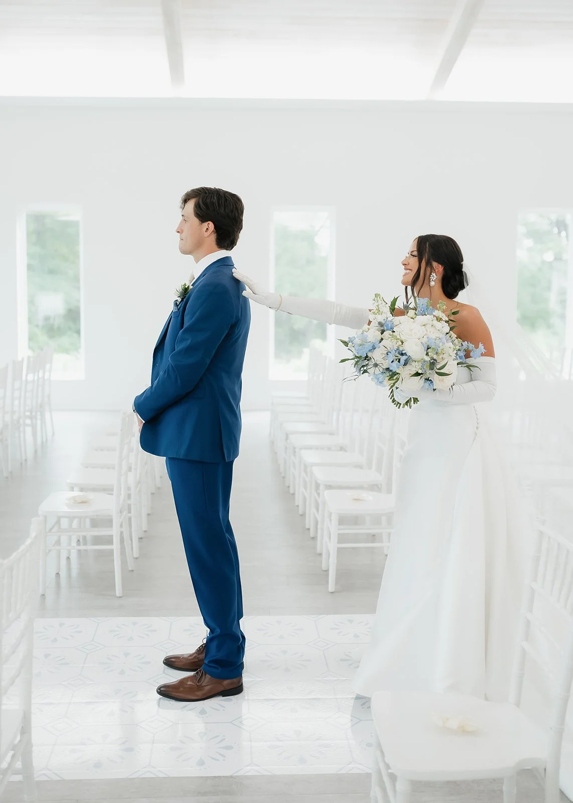 Bride taps groom on the shoulder during first look.