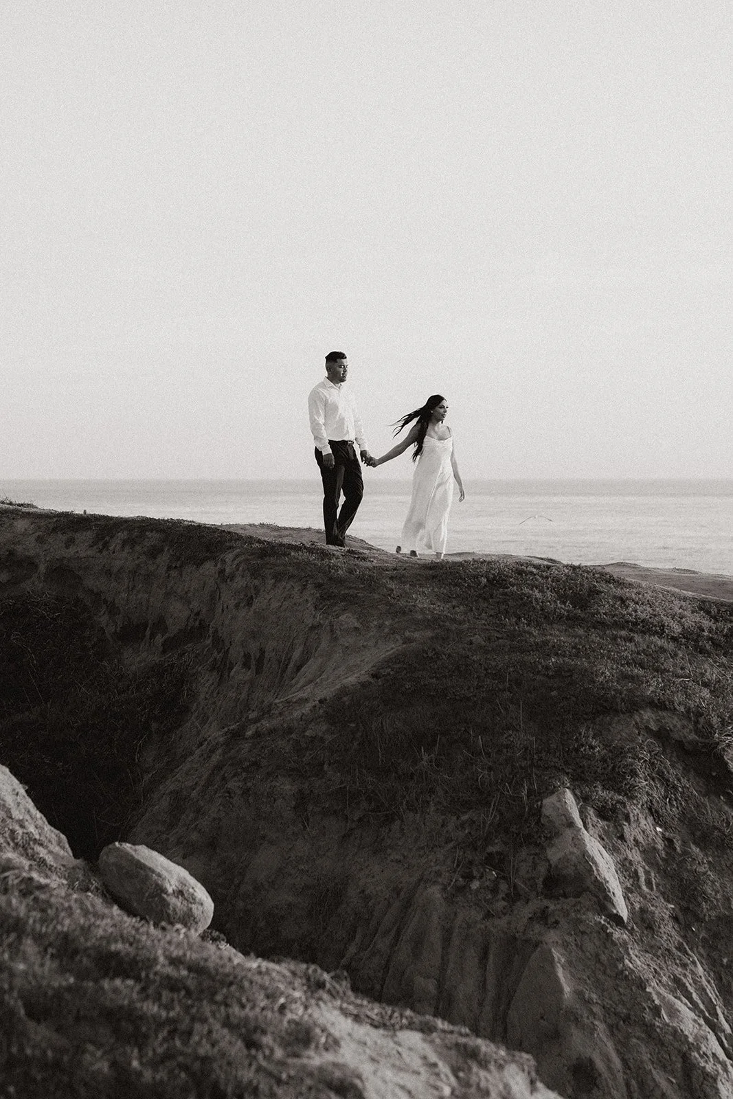 Coastal engagement portrait of couple beside the shoreline at sunset.