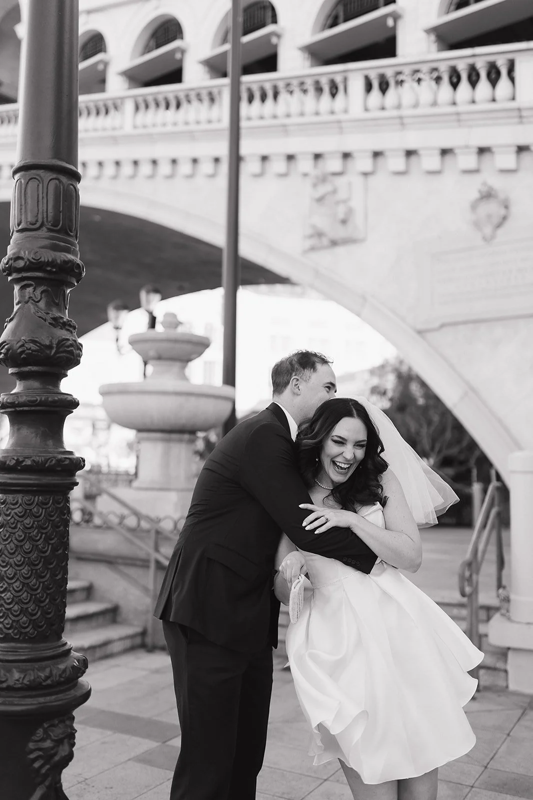 Bride and groom laughing together during composed engagement portrait.