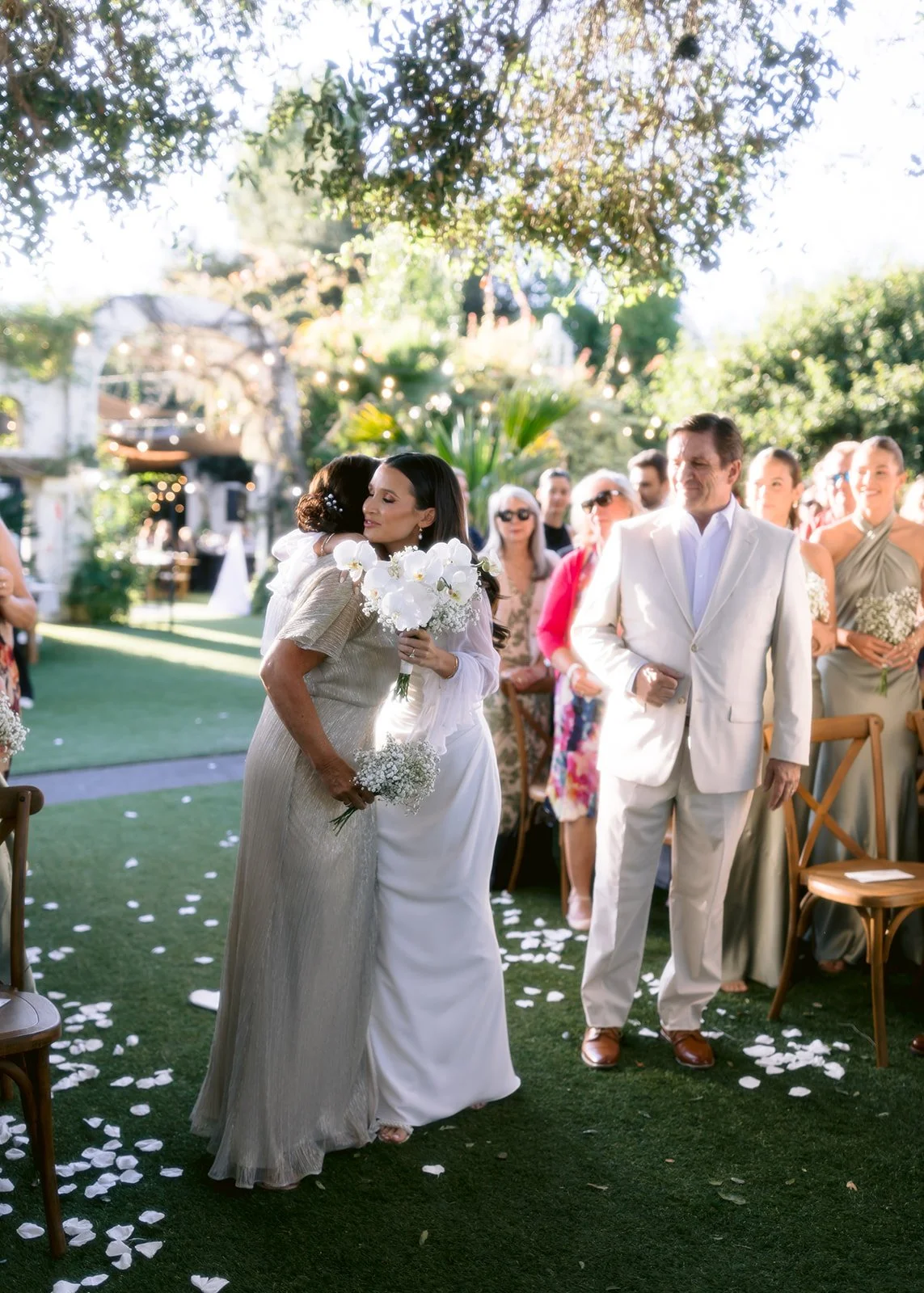 Bride and mom hug at front of wedding aisle.