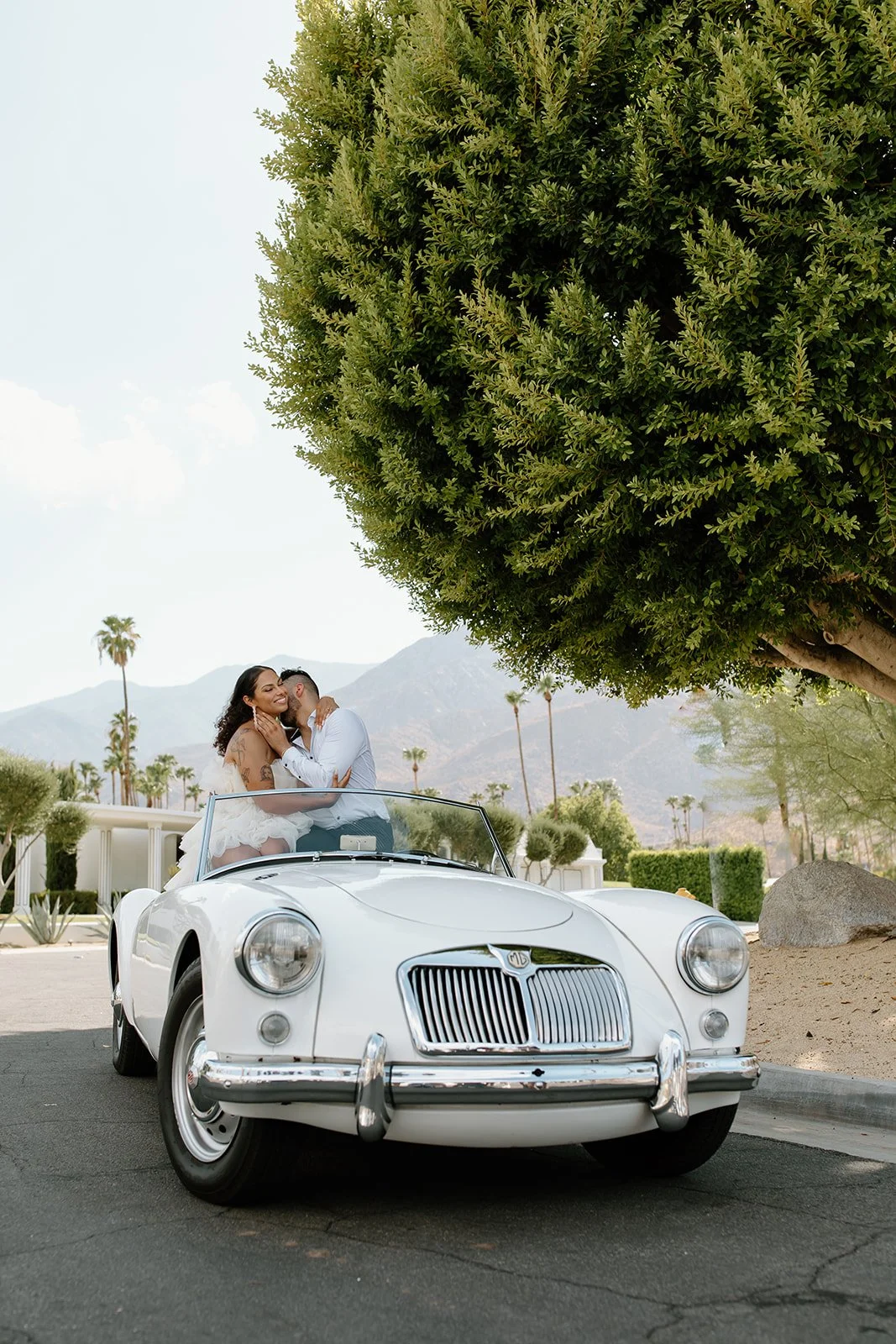 Couple posed inside vintage car during styled engagement session.