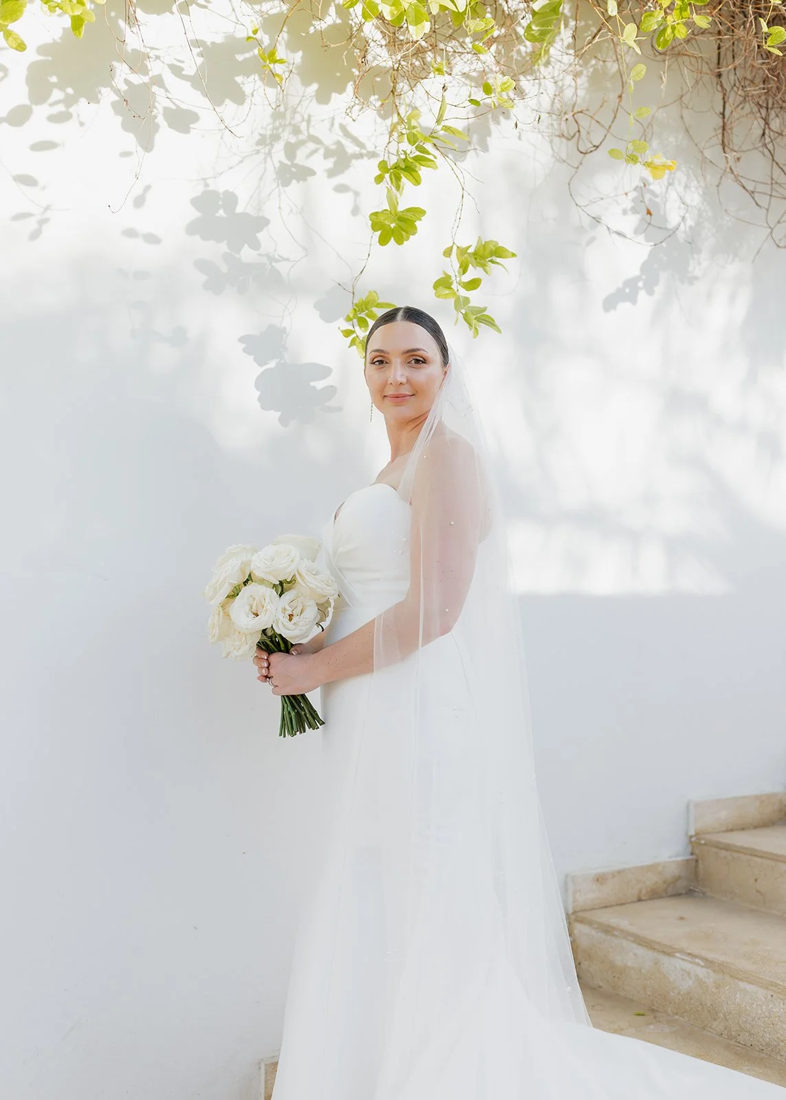 Bride poses amongst greenery during this beach wedding.