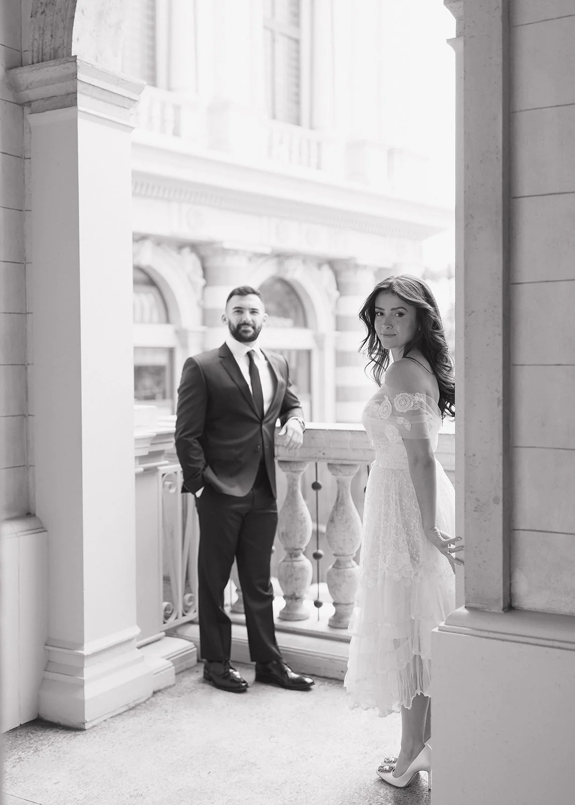 Couple posed beneath grand architectural archway during portrait session.