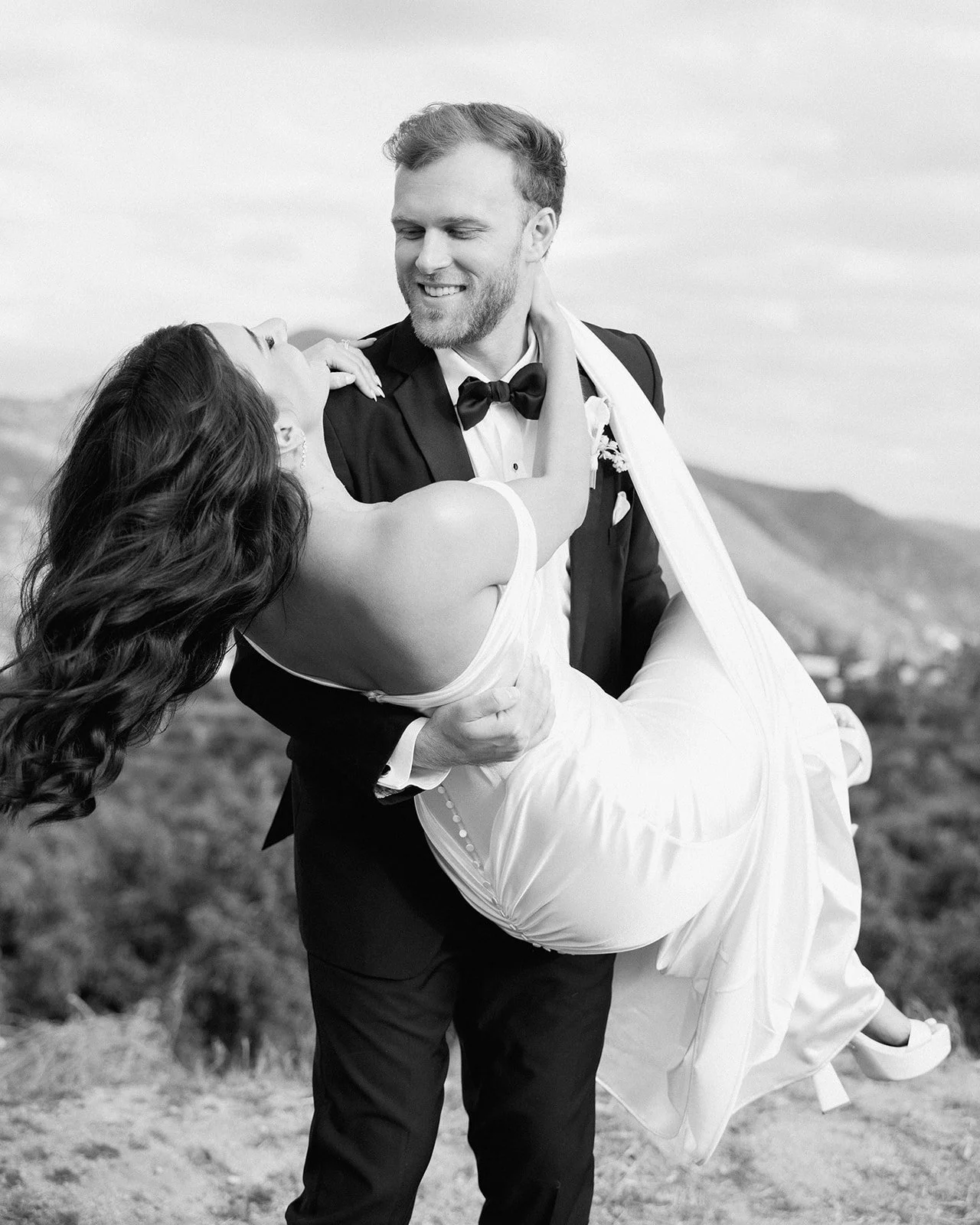 Joyful wedding couple sharing candid moment outdoors.