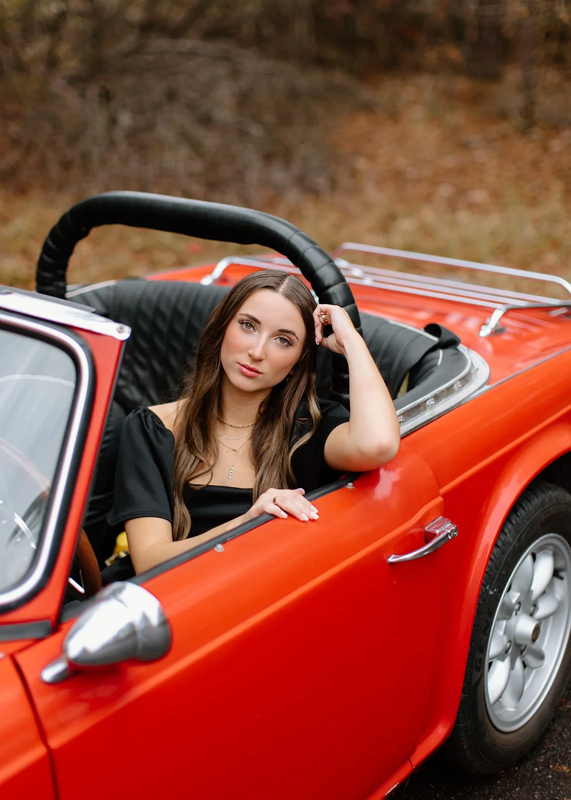 High school senior leaning against vintage car during portrait session.