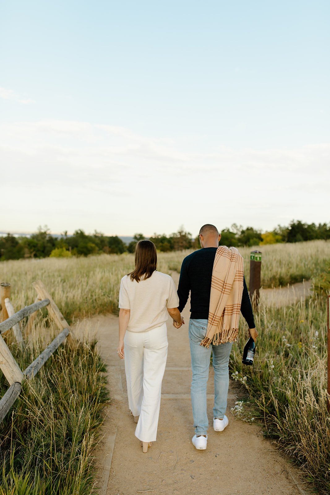 Engagement portrait captured in open green landscape with soft light.