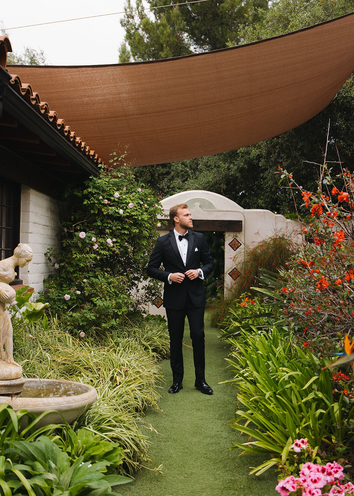 The groom posed in a garden setting at an upscale venue.