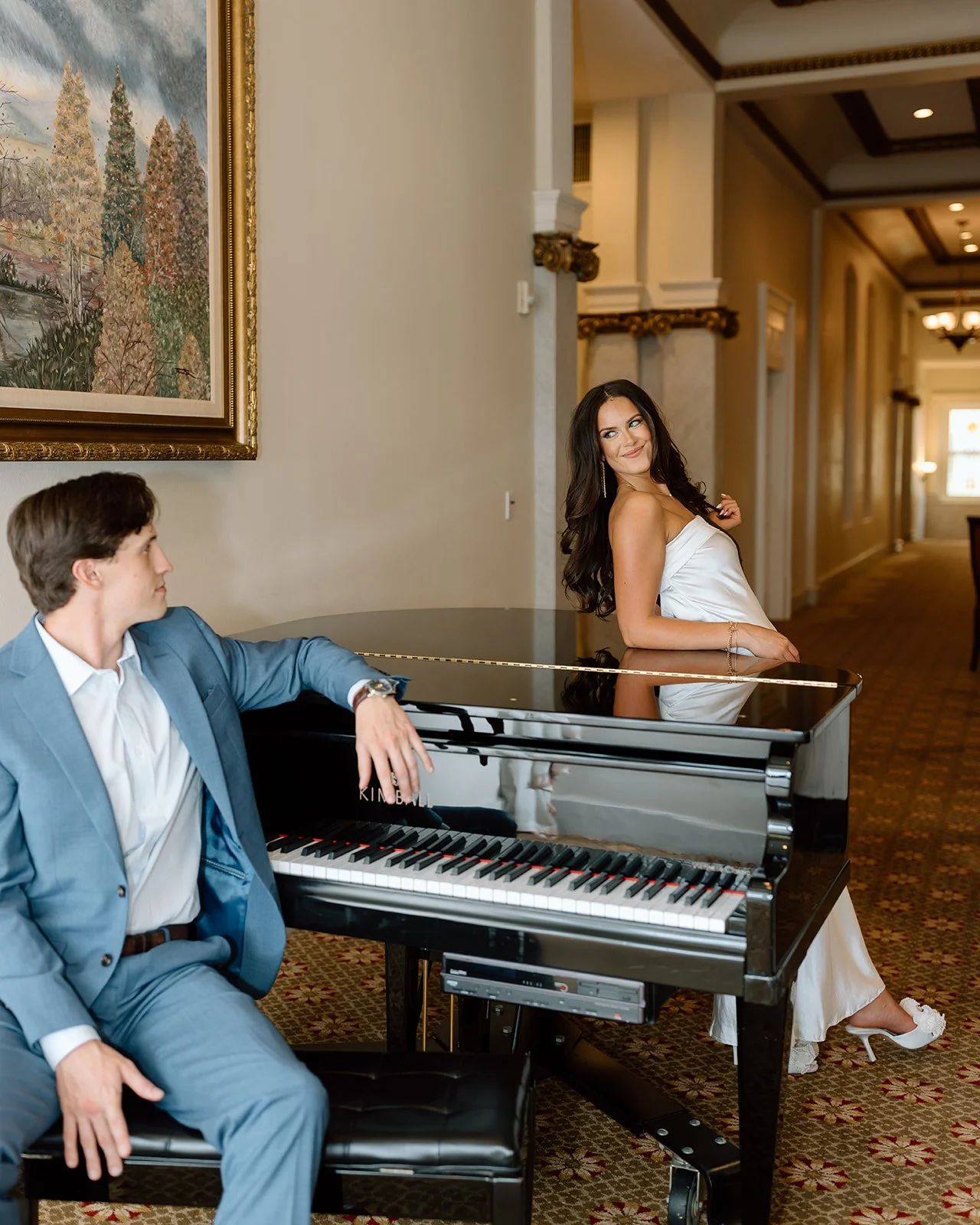 Couple posed beside piano during elegant engagement portrait session.