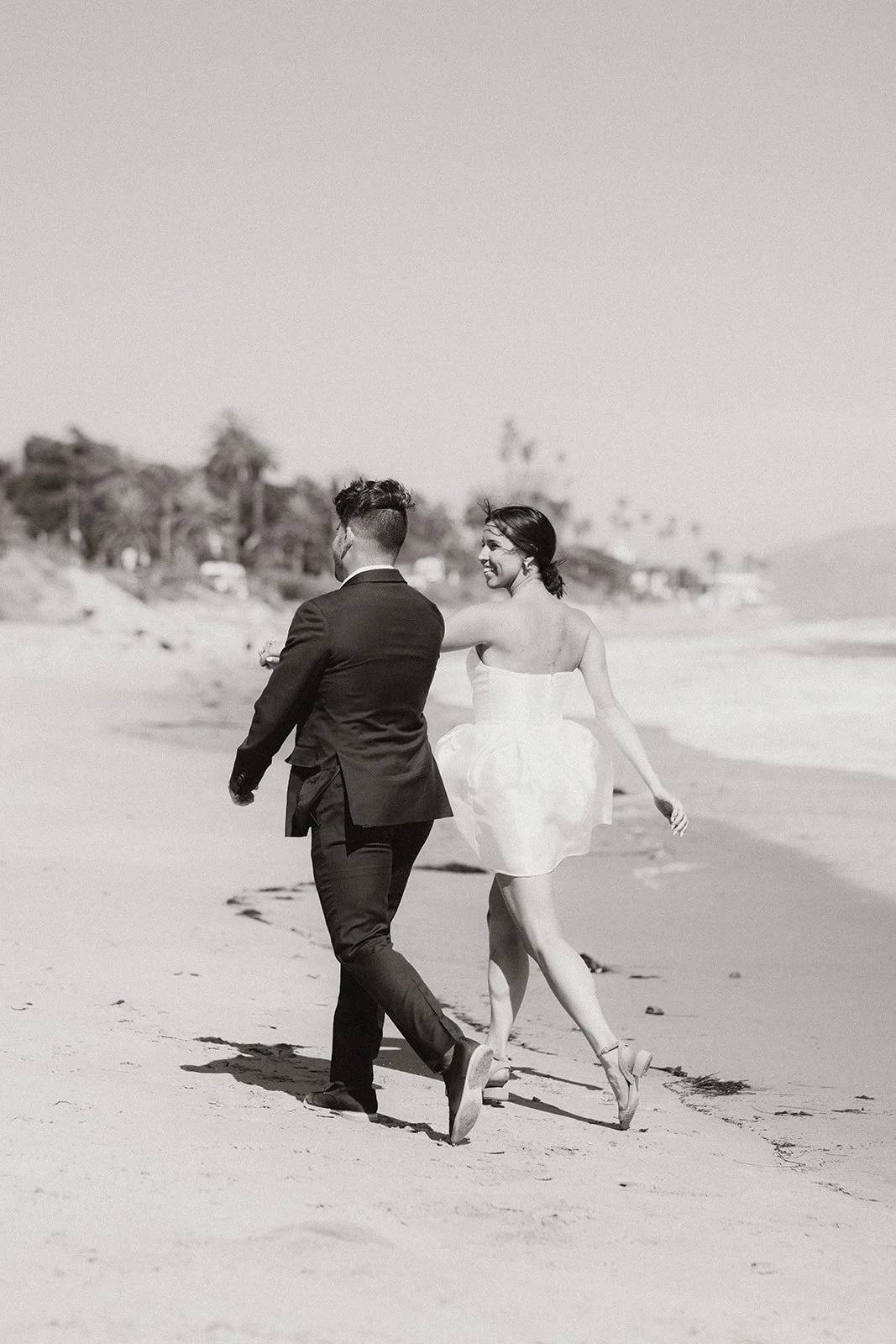 Couple walking together during golden hour engagement session on the beach.