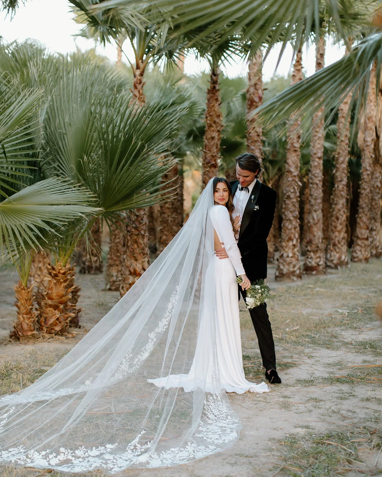 Bride and groom pose in the palm tree forest.